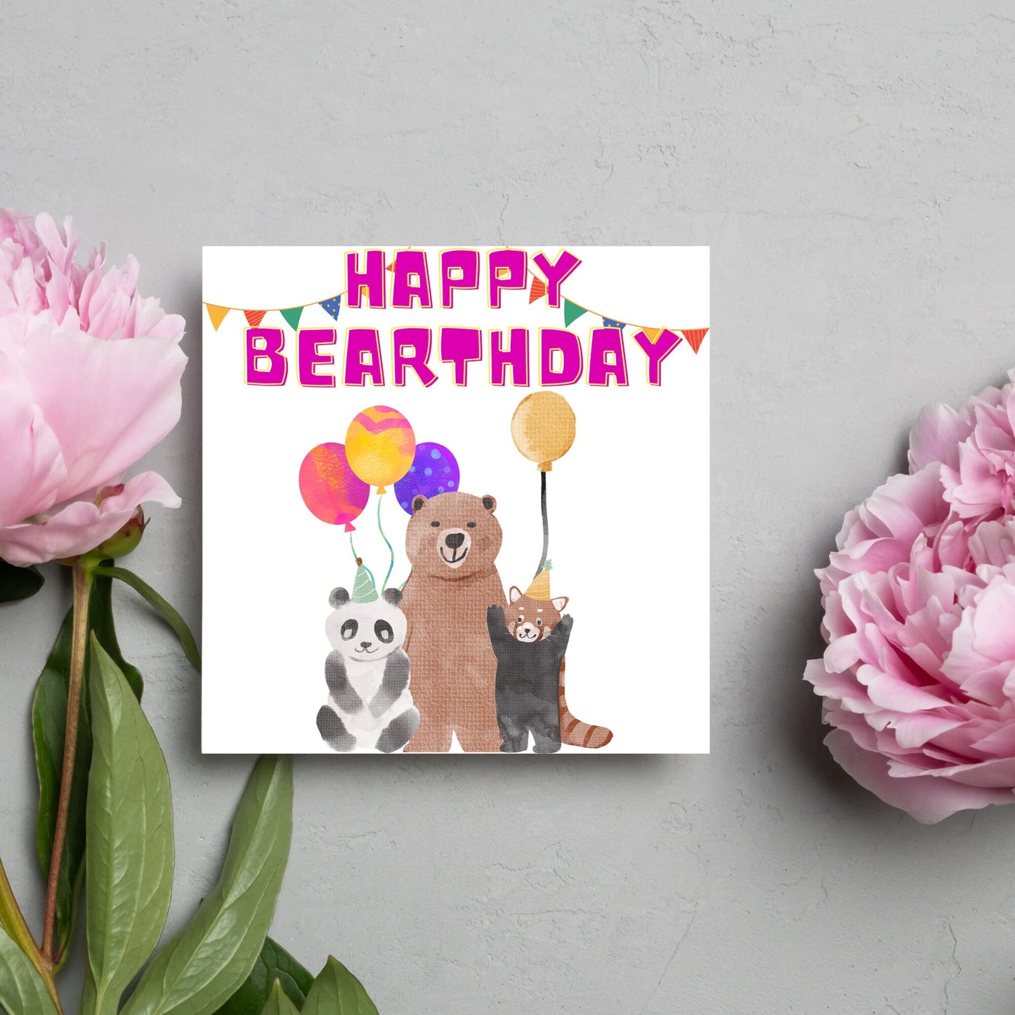 Image of a square Birthday Card. The card has a white background with a vibrant watercolour illustration of 3 bears holding balloons and big pink text that reads happy bearthday, a cute play on the traditional happy birthday.