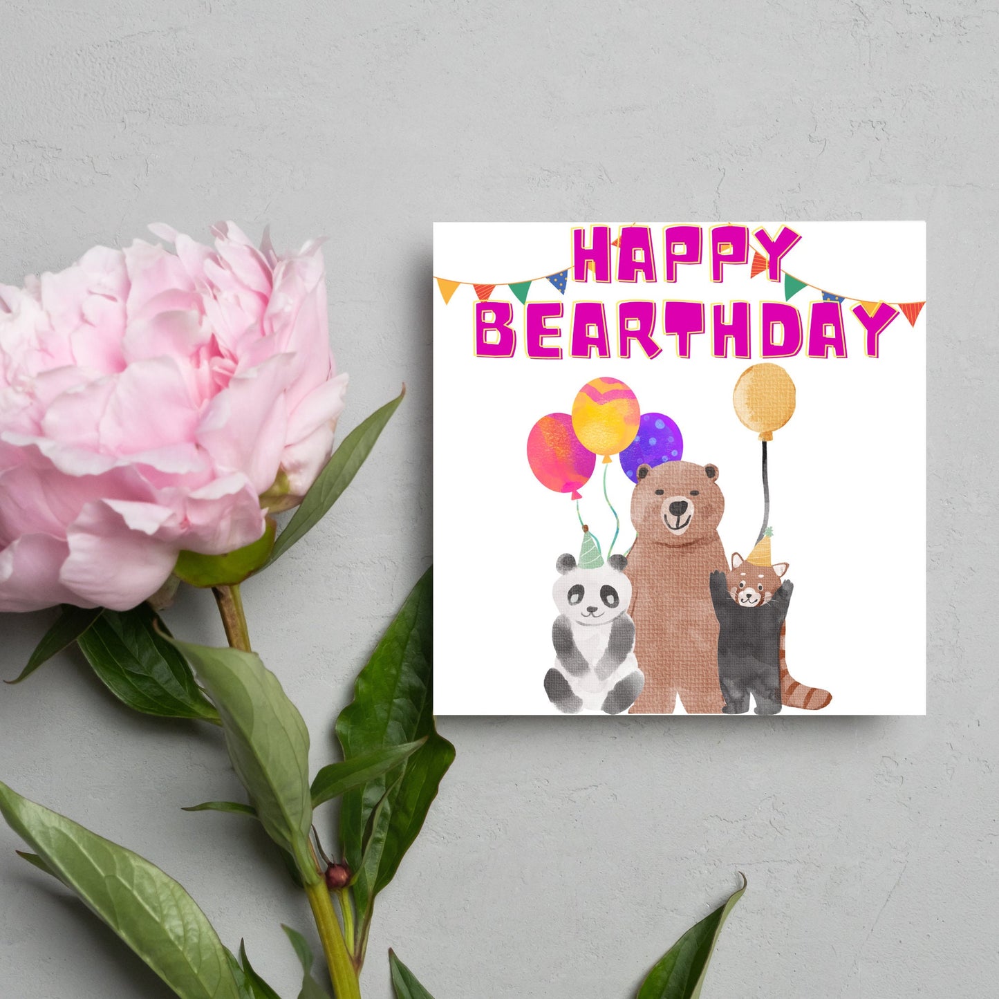 Image of a square Birthday Card. The card has a white background with a vibrant watercolour illustration of 3 bears holding balloons and big pink text that reads happy bearthday, a cute play on the traditional happy birthday.