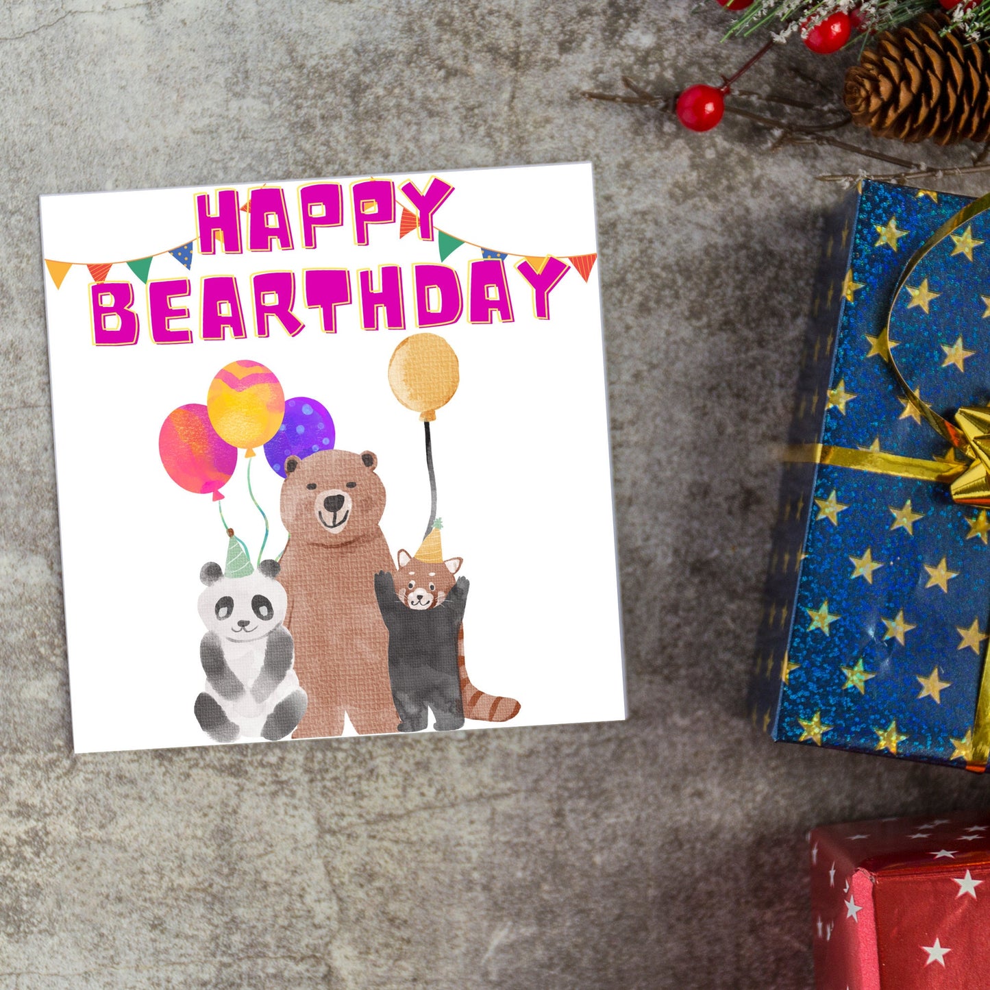 Image of a square Birthday Card. The card has a white background with a vibrant watercolour illustration of 3 bears holding balloons and big pink text that reads happy bearthday, a cute play on the traditional happy birthday.