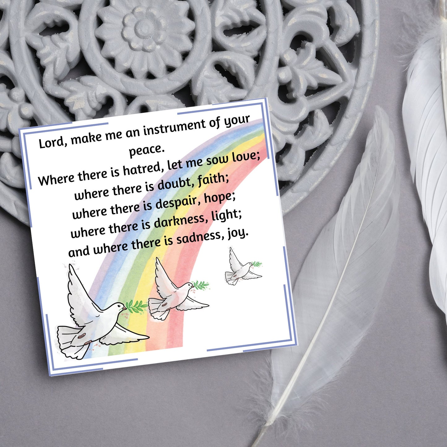 Square greetings card with 3 flying peace doves against a rainbow, with the Prayer of Saint Francis text Lord, make me an instrument of your peace.