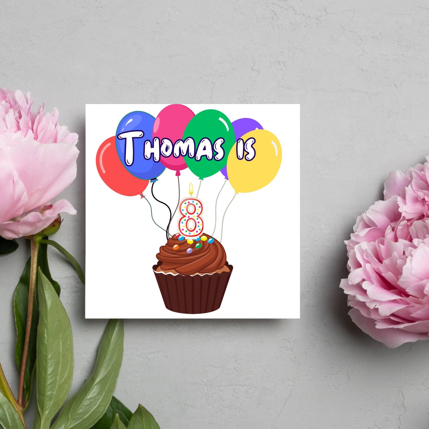 square childs birthday card with chocolate cupcake design personalised with name balloons and a number 8 candle. card reads thomas is 8