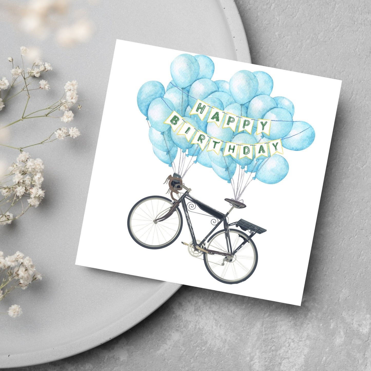 White square birthday card with an illustration of a bicycle being held aloft by blue watercolour balloons and bunting that reads happy birthday