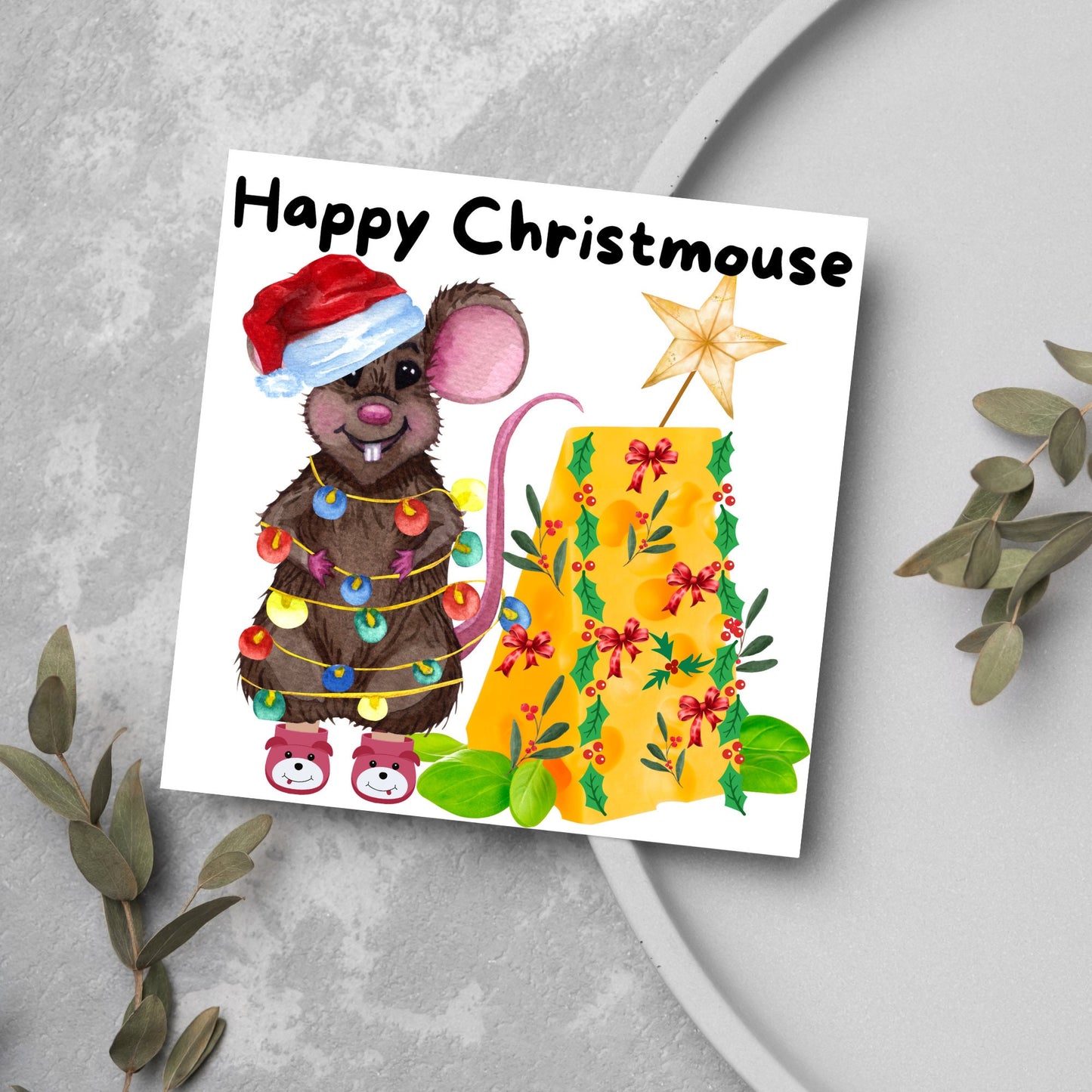 Square Christmas card featuring a cartoon mouse wrapped in christmas lights and wearing a santa hat and slippers next to a christmas tree made from cheese with decorations of holly and red bows. The text, Happy Christmouse is written at the top