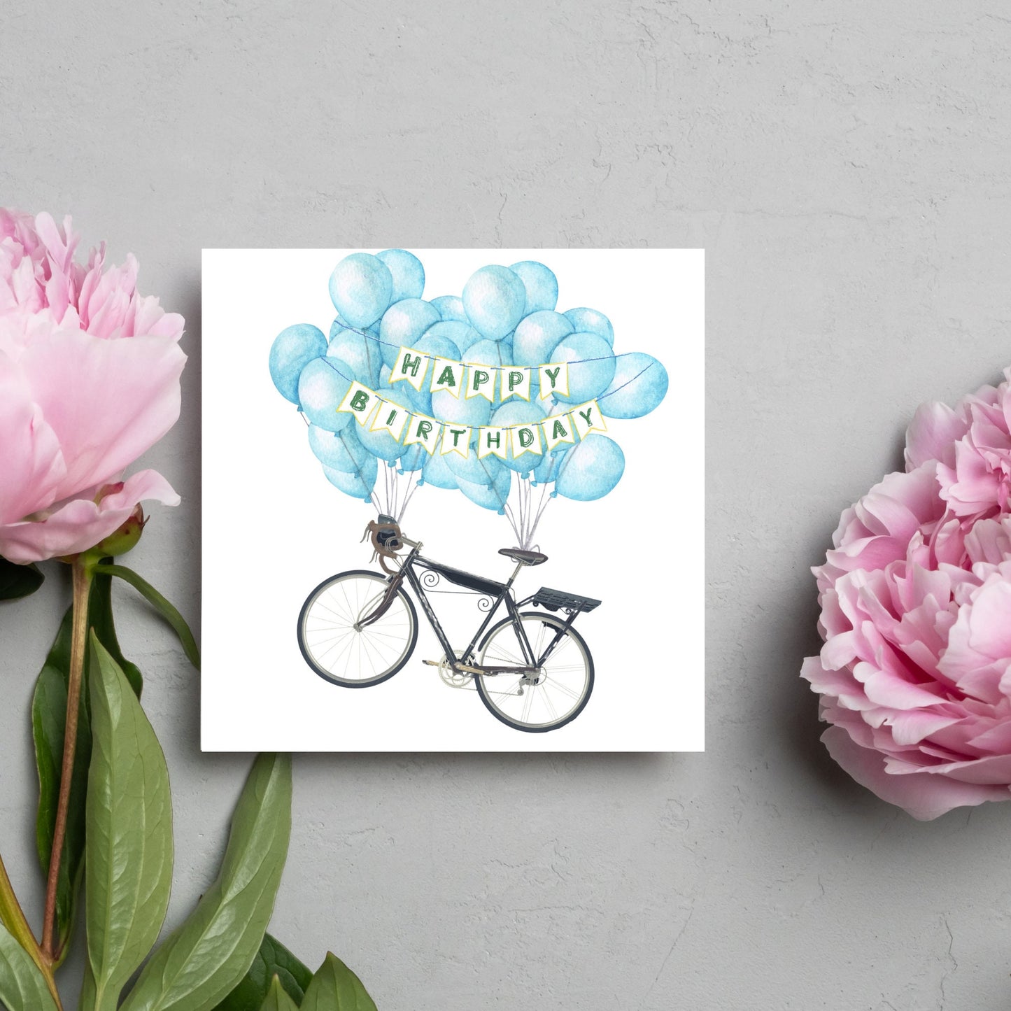White square birthday card with an illustration of a bicycle being held aloft by blue watercolour balloons and bunting that reads happy birthday