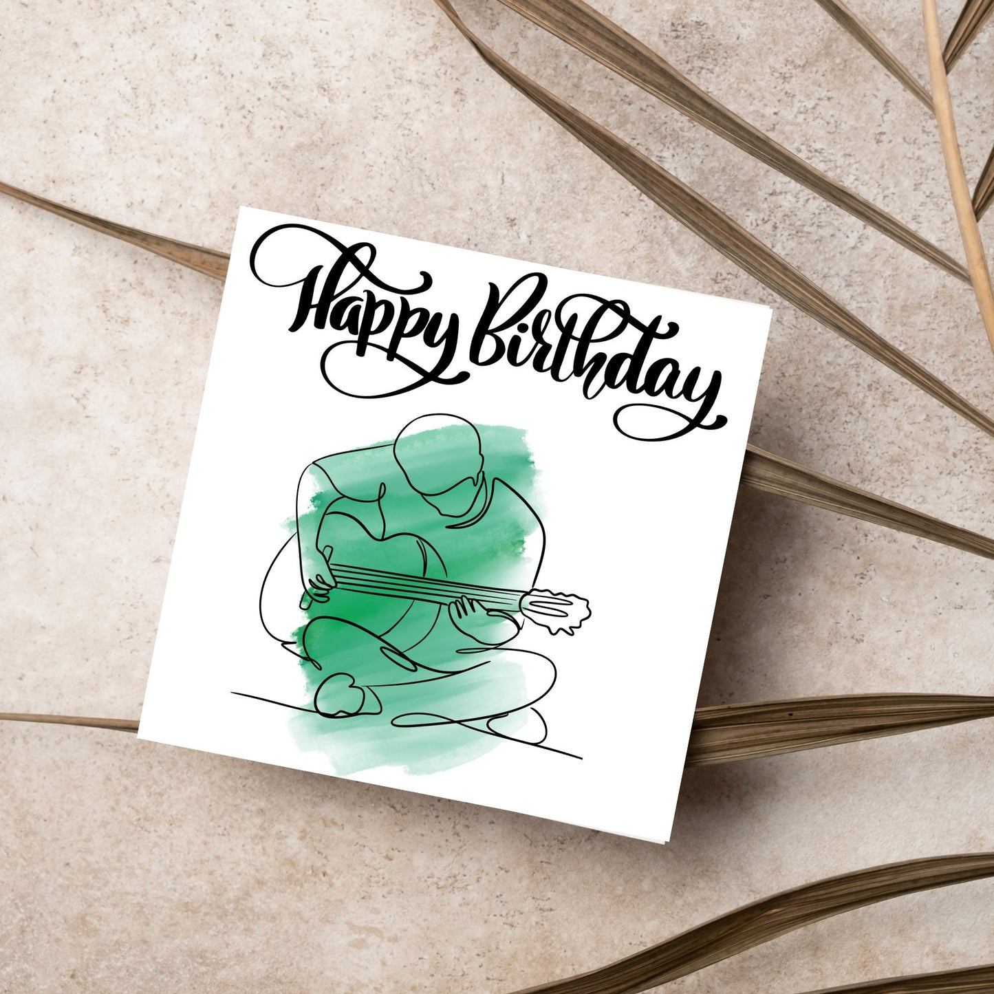 Square birthday card featuring a line drawing of a person sitting cross legged playing a guitar with a green watercolour style backdrop. The top of the card reads Happy Birthday in black swirly writing