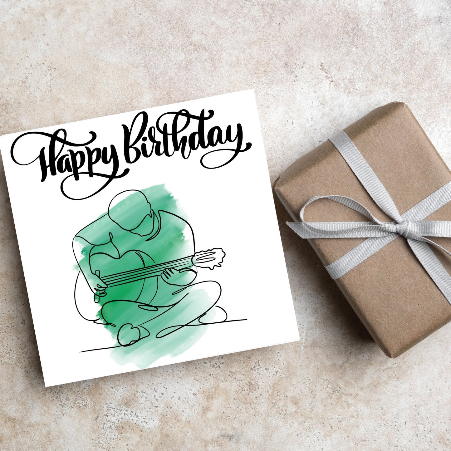 Square birthday card featuring a line drawing of a person sitting cross legged playing a guitar with a green watercolour style backdrop. The top of the card reads Happy Birthday in black swirly writing