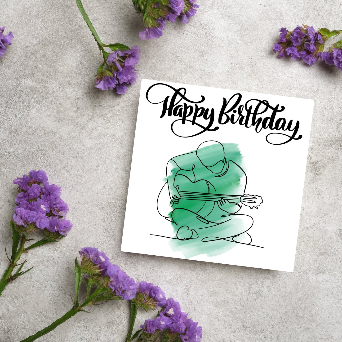 Square birthday card featuring a line drawing of a person sitting cross legged playing a guitar with a green watercolour style backdrop. The top of the card reads Happy Birthday in black swirly writing