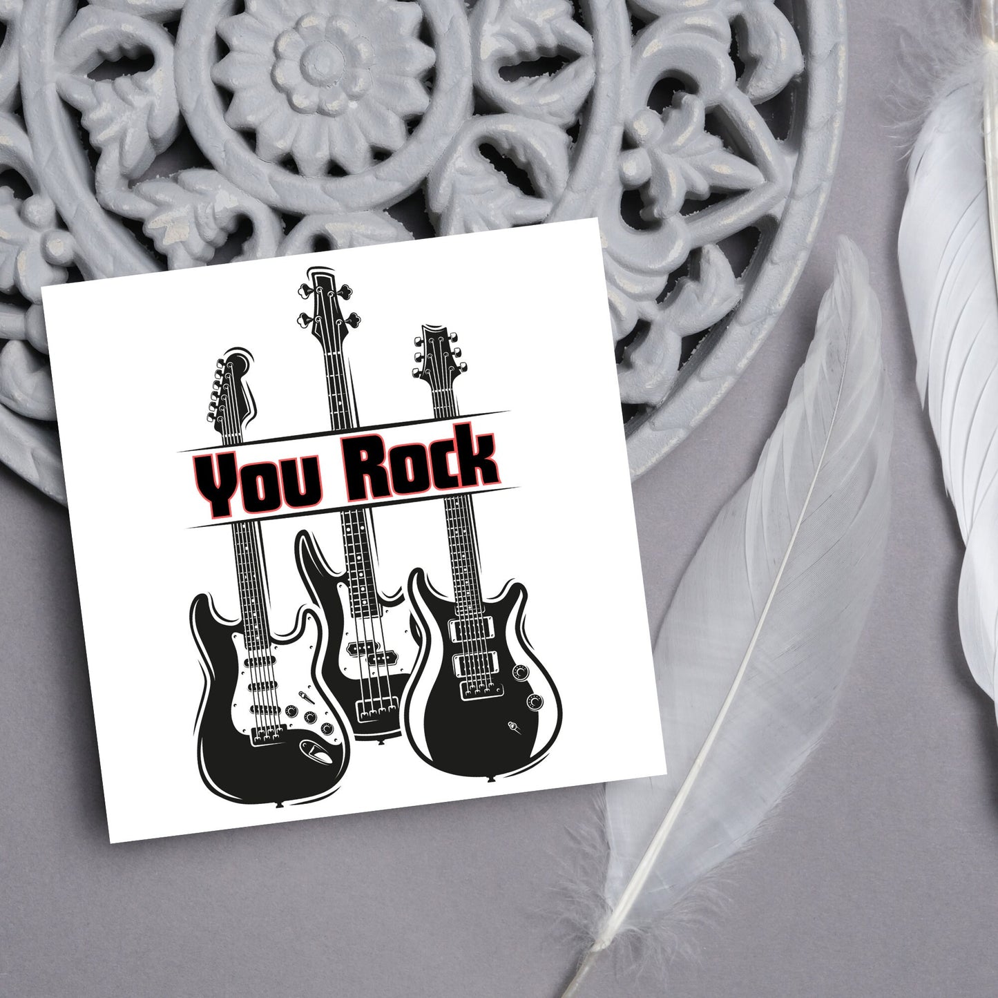 Square Greetings card featuring 3 black electric guitars with 'you rock' written across them in red and black
