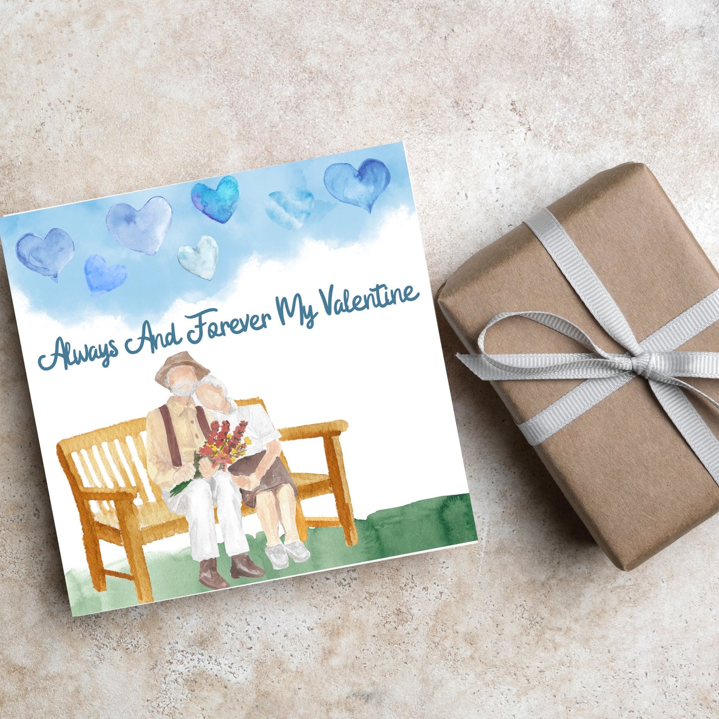 This beautiful Card has a watercolour style print with a couple sitting on a bench with flowers. Above them the blue sky has a series of cute watercolour hearts. This Cute card is perfect for valentines day for your wife or husband