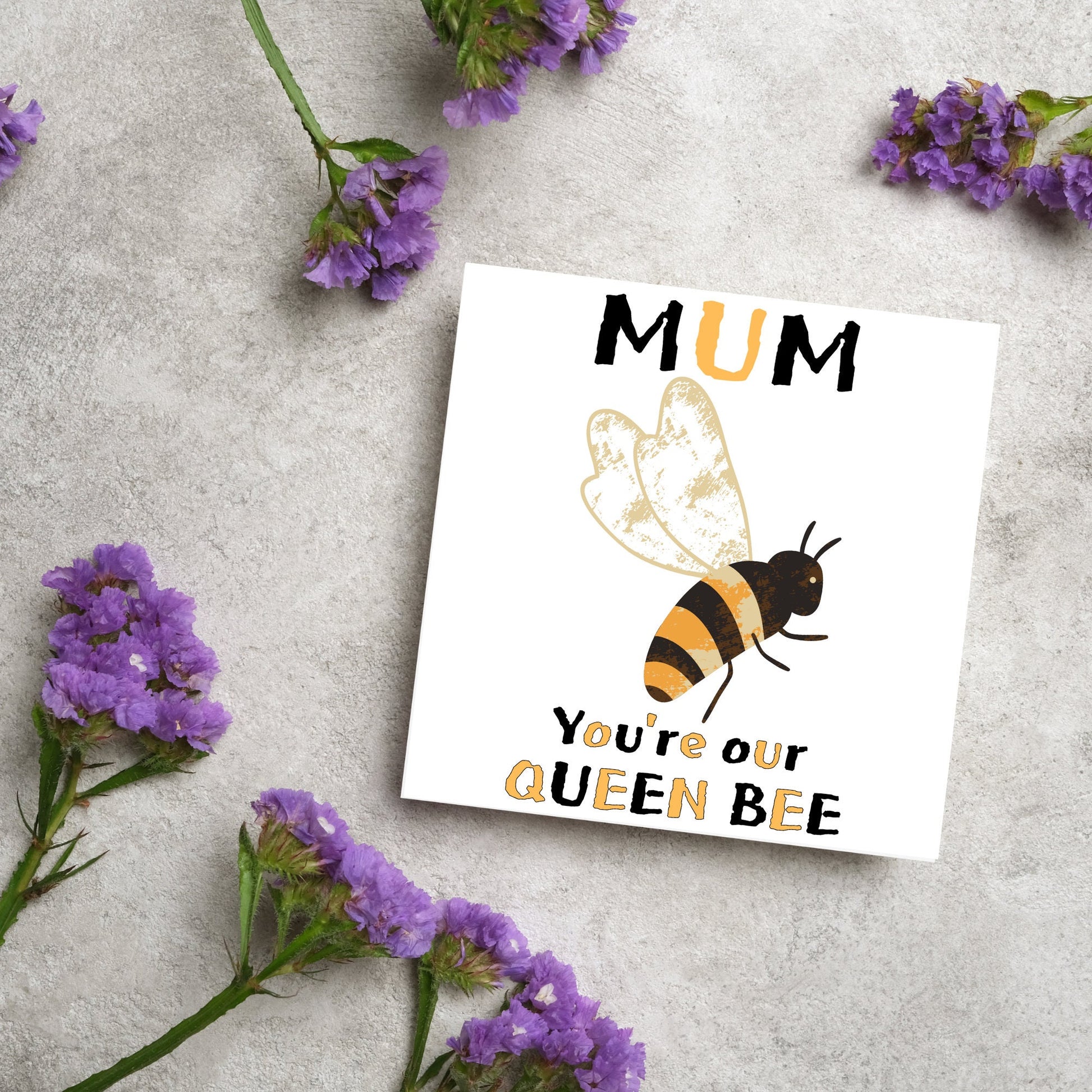 square Birthday card with a watercolour illustration of a bee in the centre and yellow and black text which reads , mum youre our queen bee, in a textured style font resembling pollen