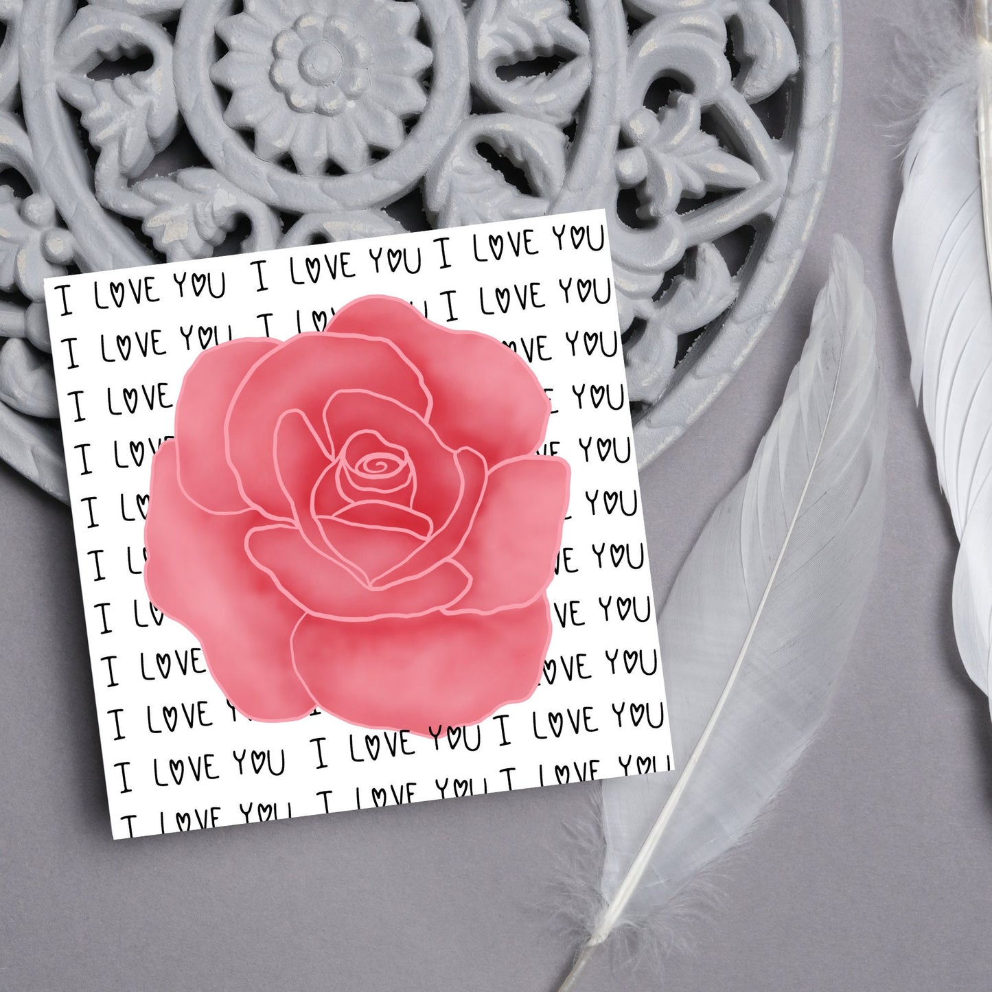 simple elegant card for valentines or anniversary, featuring a large pink rose painting with a background of handwritten style text that repeats 'I love you' with hearts instead of o's