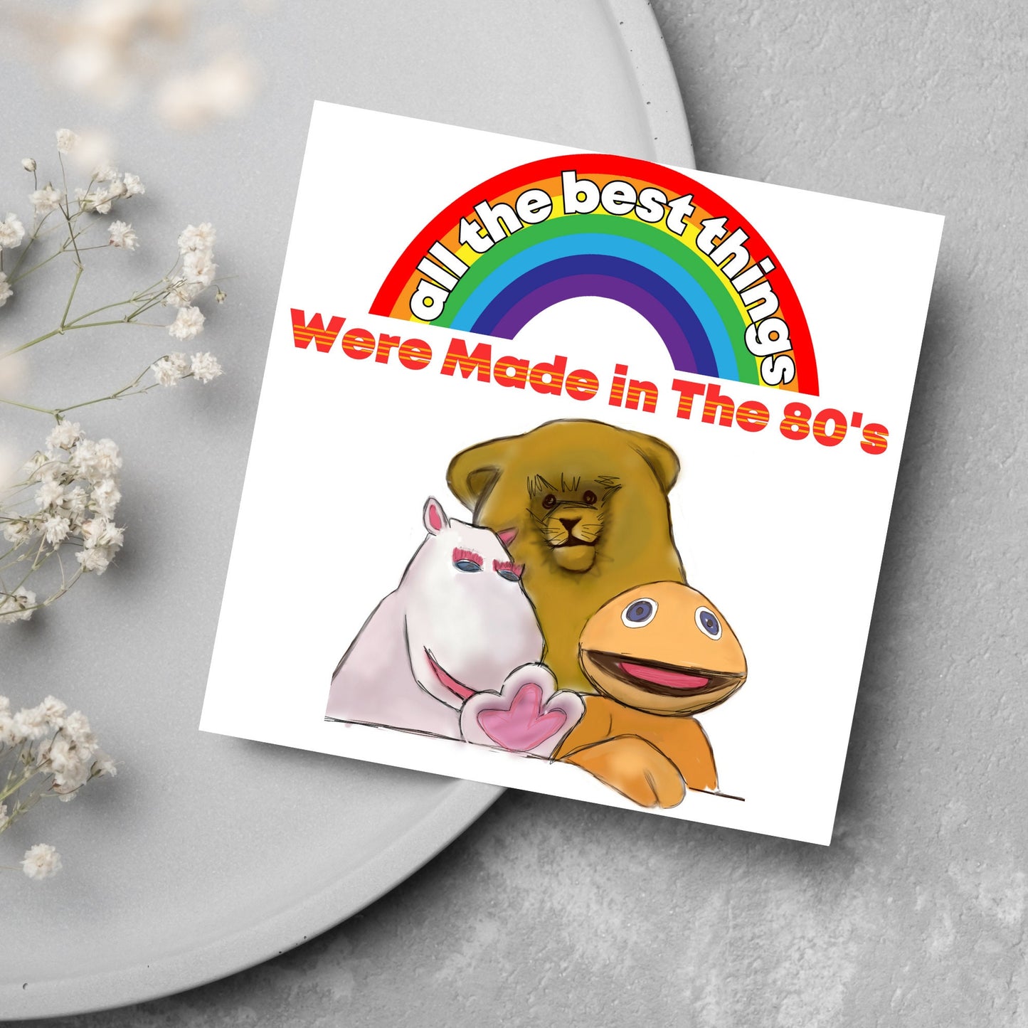 square card featuring an illustration of the characters from the tv show rainbow with a rainbow and red text that reads 'all the best things were' made in the 80's' in the font from the shows title