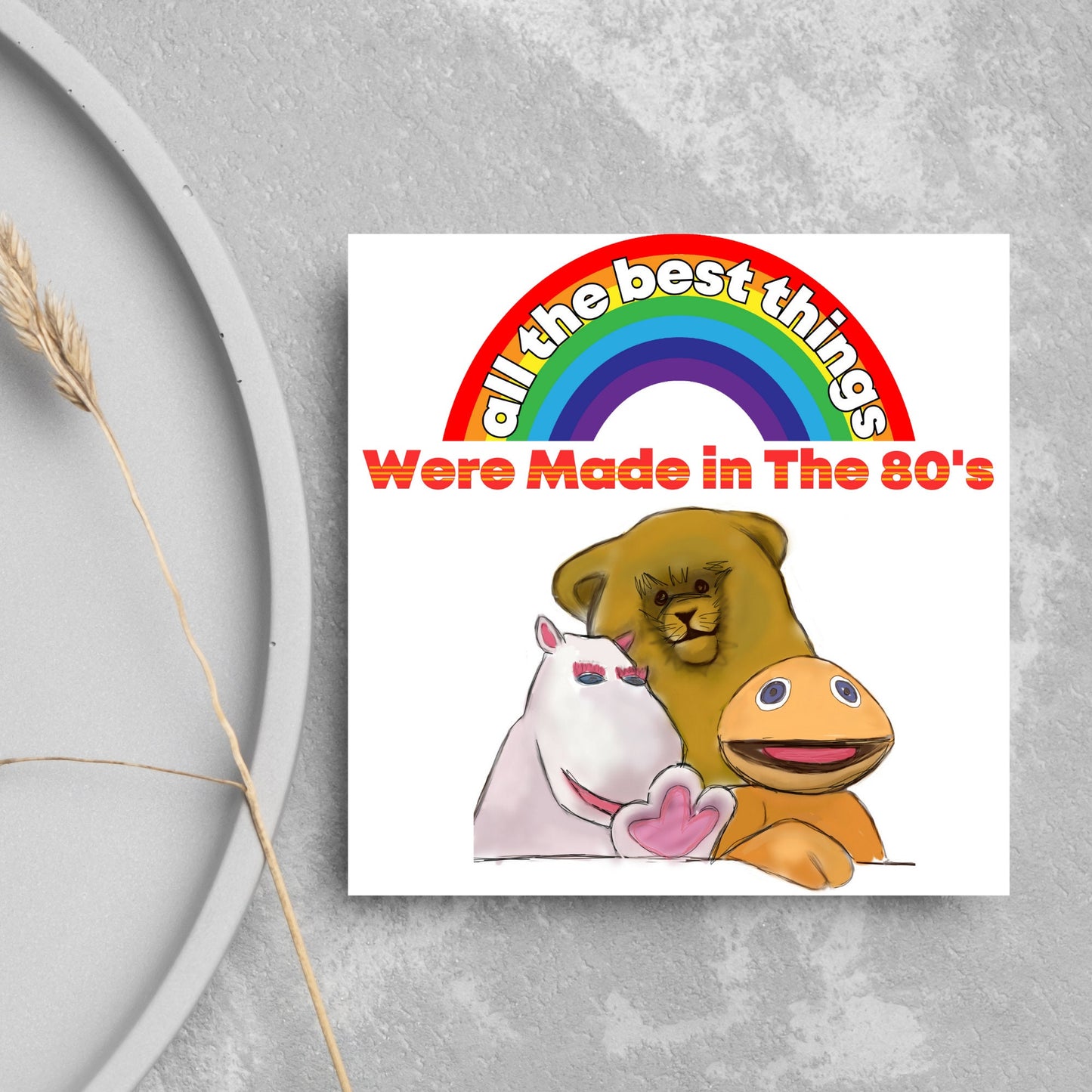 square card featuring an illustration of the characters from the tv show rainbow with a rainbow and red text that reads 'all the best things were' made in the 80's' in the font from the shows title