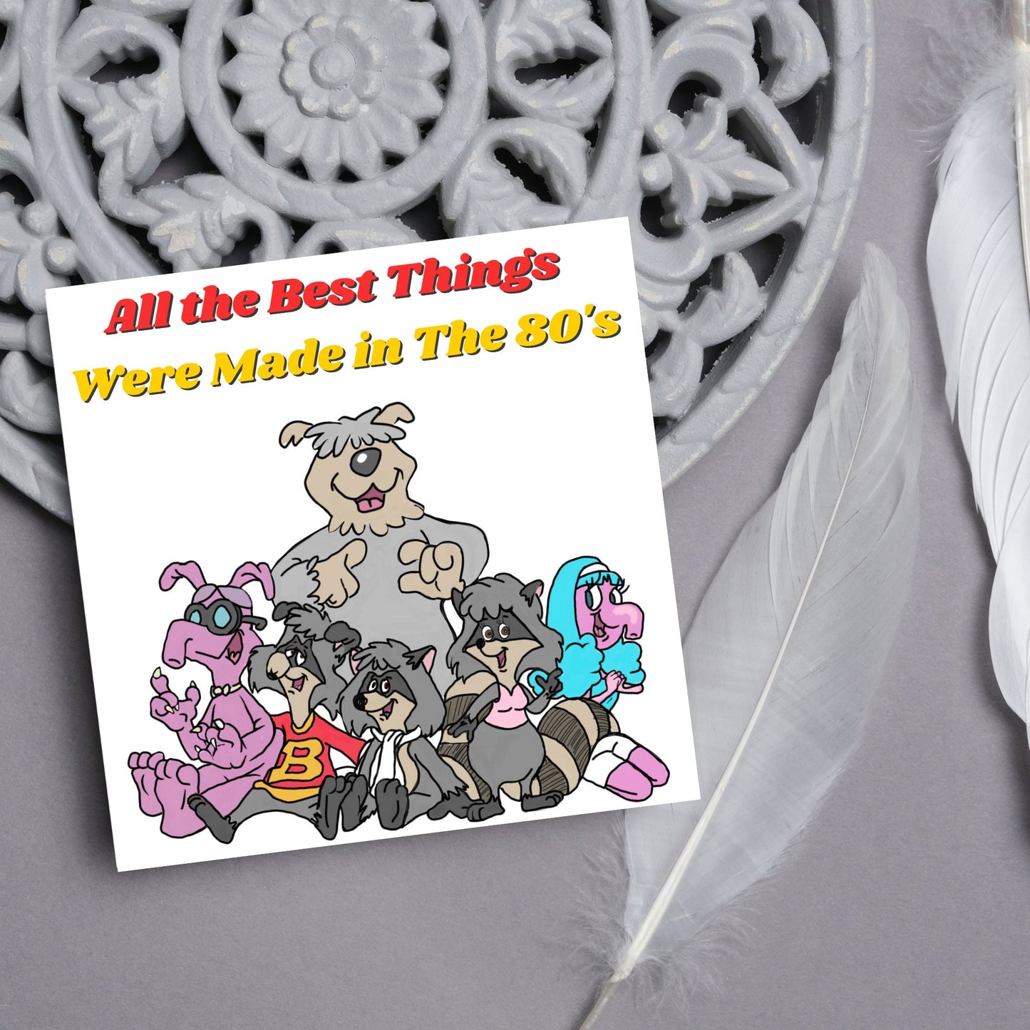 square card featuring an illustration of the raccoons from the tv cartoon with yellow and red text that reads 'all the best things were' made in the 80's' in the font from the shows title
