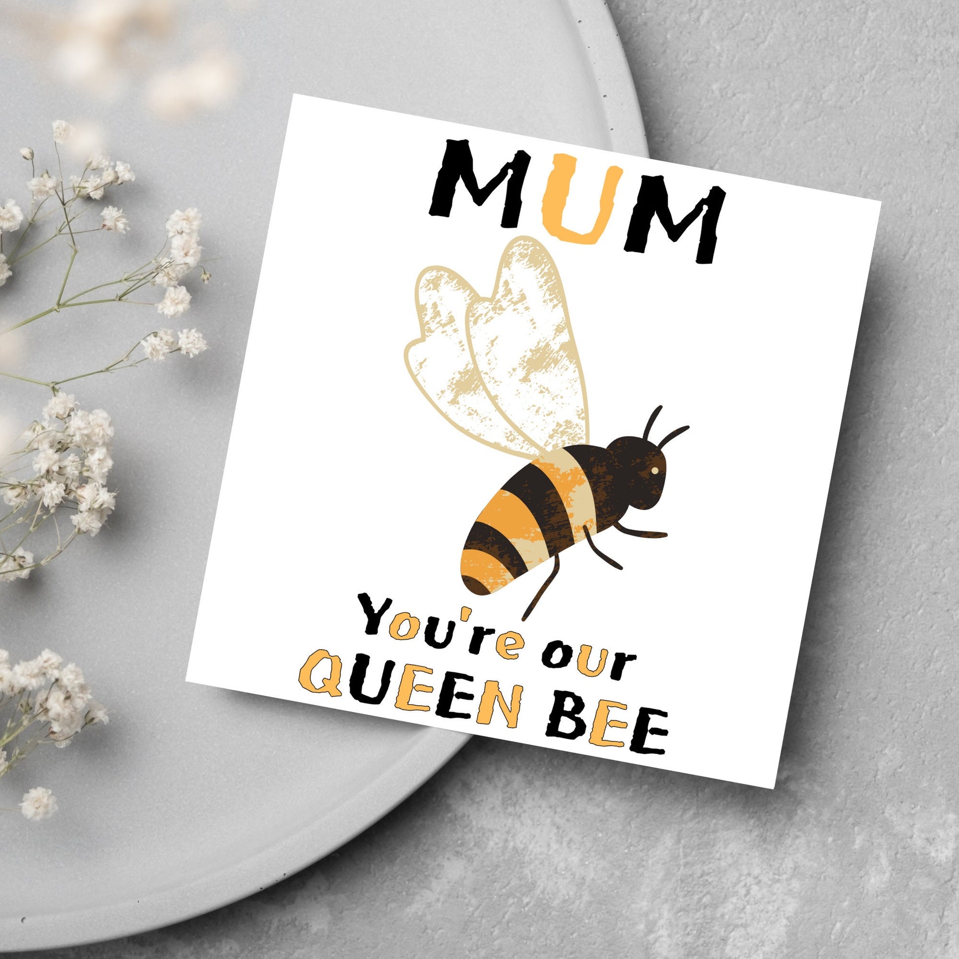 square Birthday card with a watercolour illustration of a bee in the centre and yellow and black text which reads , mum youre our queen bee, in a textured style font resembling pollen