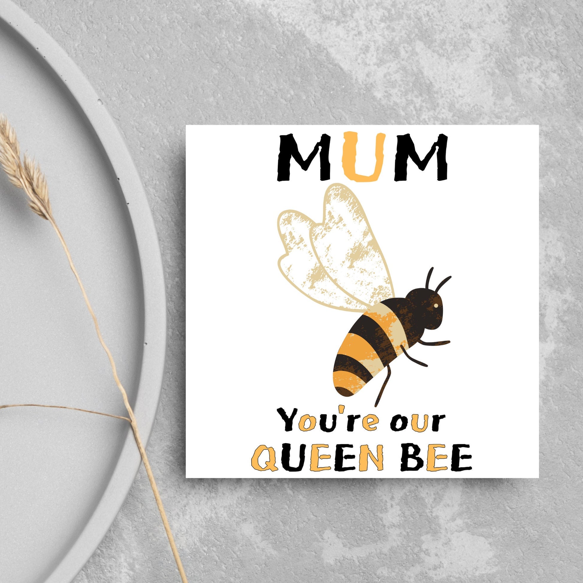 square Birthday card with a watercolour illustration of a bee in the centre and yellow and black text which reads , mum youre our queen bee, in a textured style font resembling pollen