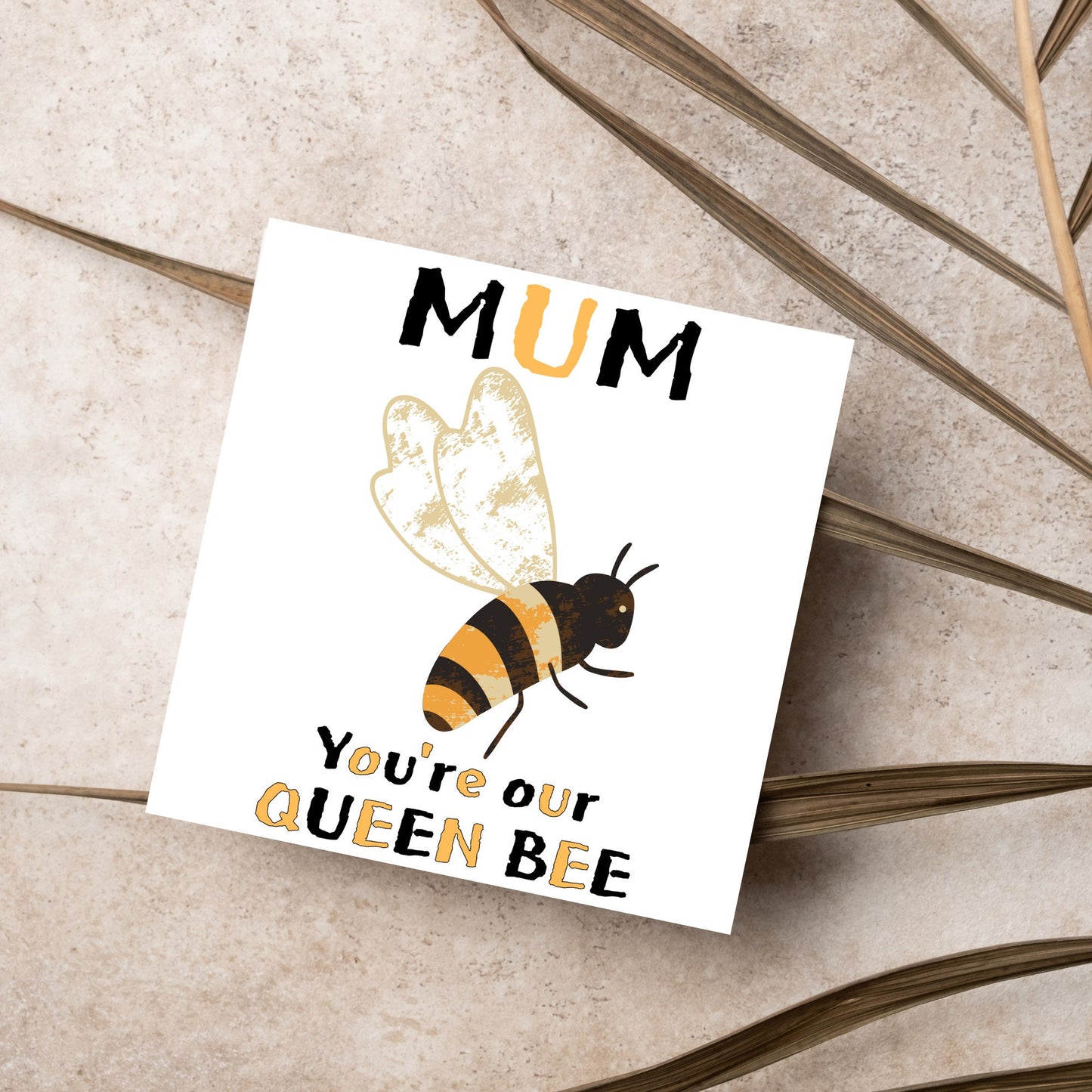 square Birthday card with a watercolour illustration of a bee in the centre and yellow and black text which reads , mum youre our queen bee, in a textured style font resembling pollen