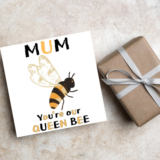 square Birthday card with a watercolour illustration of a bee in the centre and yellow and black text which reads , mum youre our queen bee, in a textured style font resembling pollen