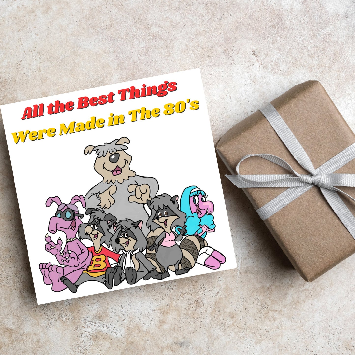 square card featuring an illustration of the raccoons from the tv cartoon with yellow and red text that reads 'all the best things were' made in the 80's' in the font from the shows title