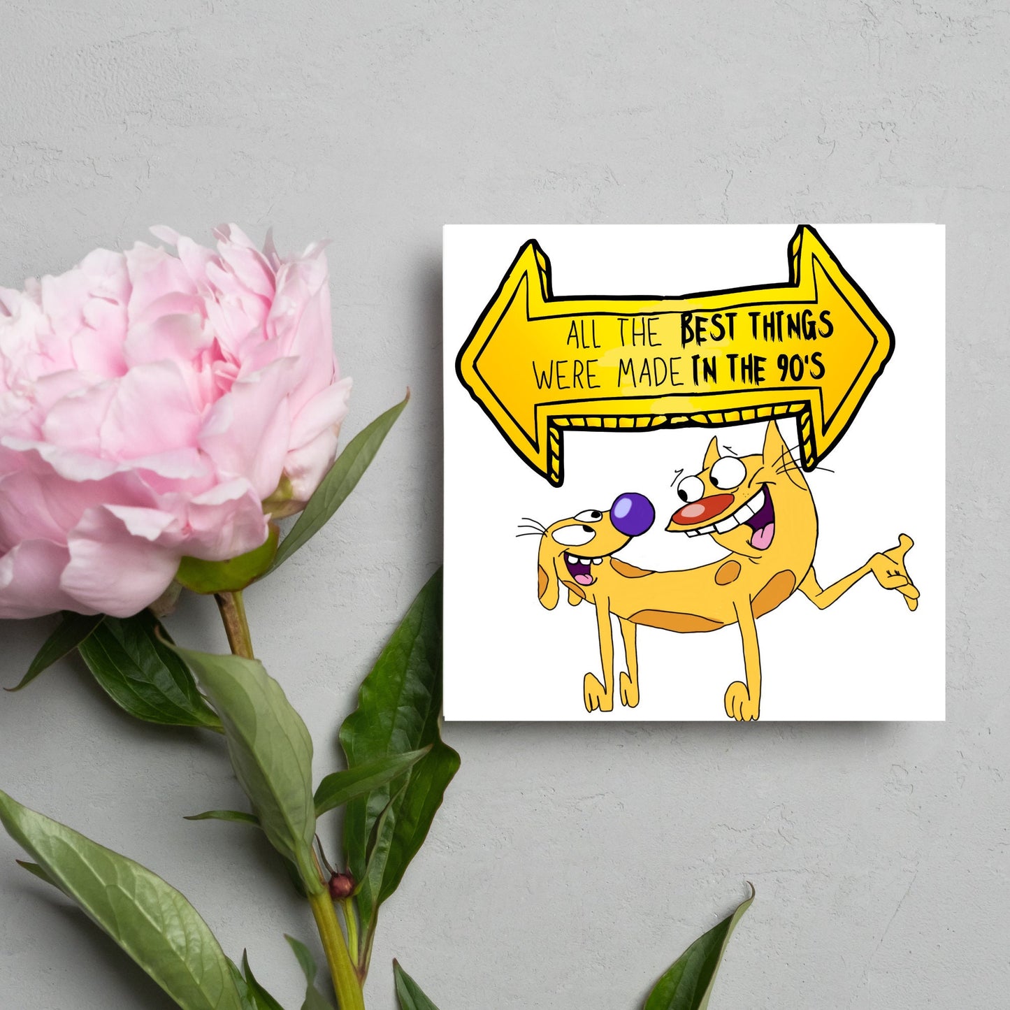square card featuring an illustration of catdog with a yellow and black sign above them with the text that reads 'all the best things were' made in the 90's' in the font from the shows title
