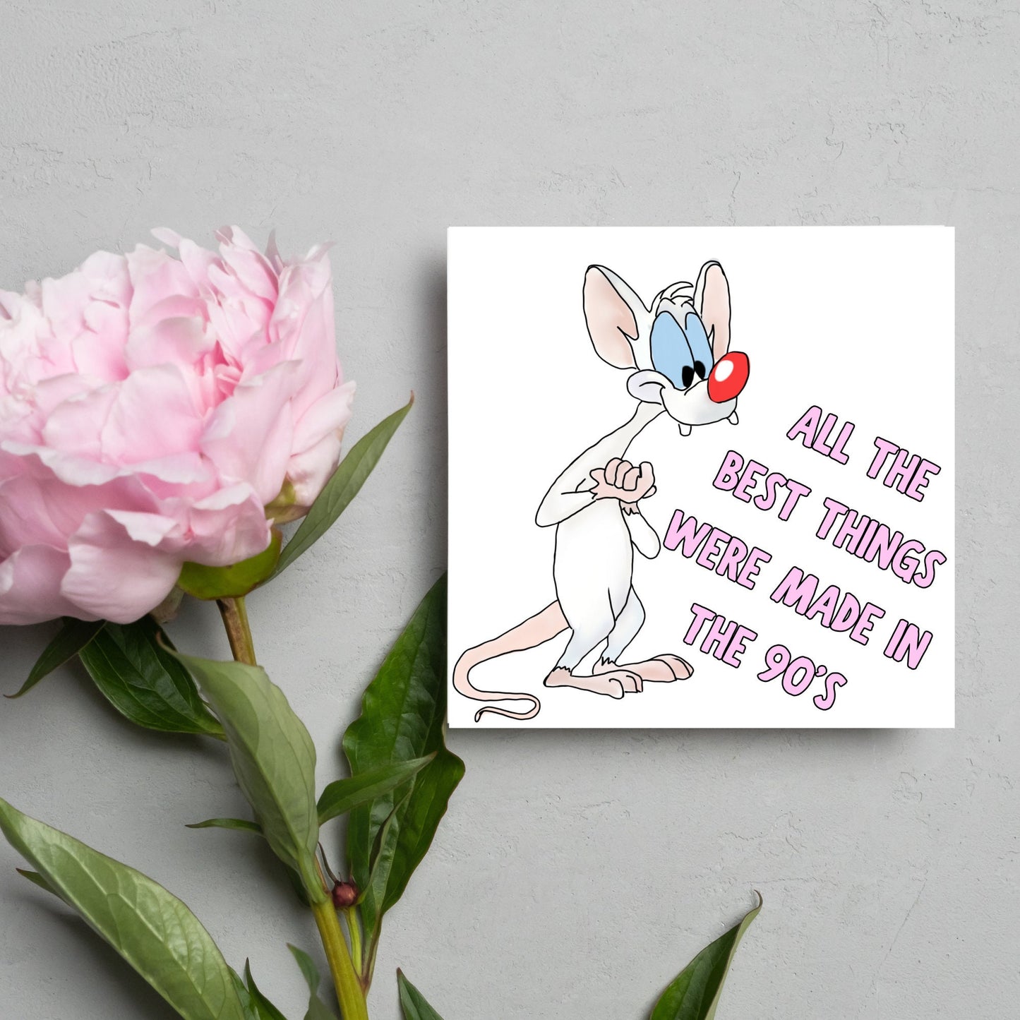 square card featuring an illustration of Pinky from Pinky and the brain with pink text text that reads 'all the best things were' made in the 90's' in the font from the shows title