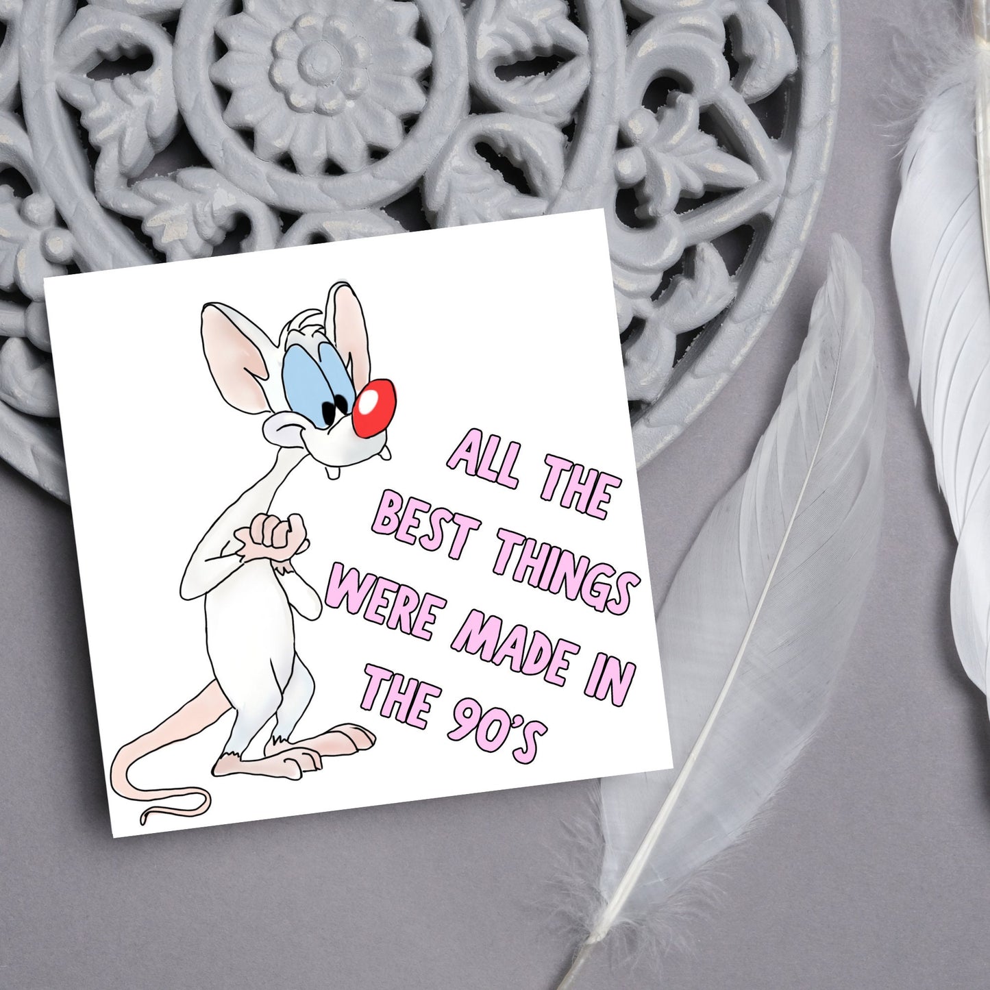 square card featuring an illustration of Pinky from Pinky and the brain with pink text text that reads 'all the best things were' made in the 90's' in the font from the shows title