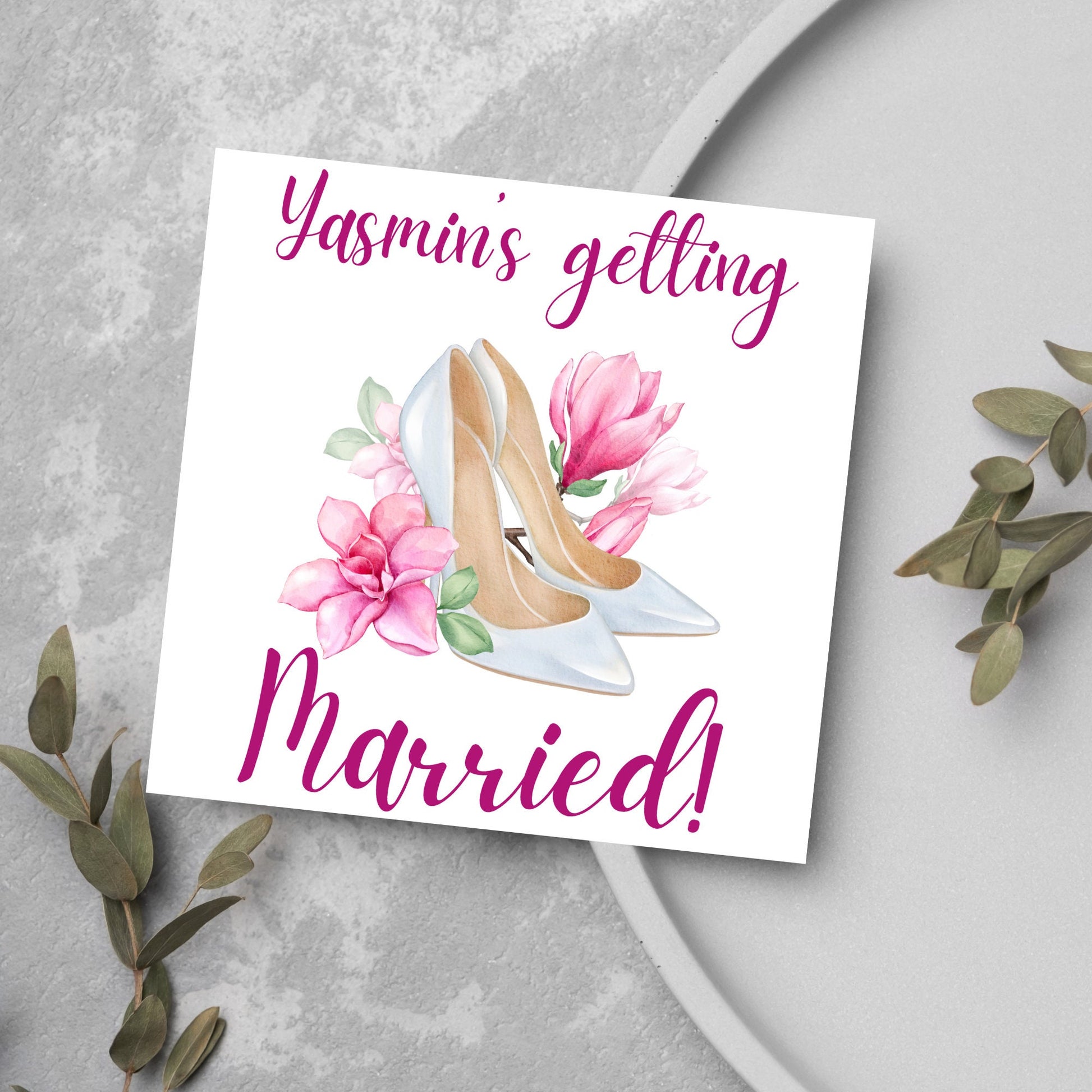 Square card with a watercolour image of white wedding shoes surrounded by pink flowers with pink text that reads Yasmin's getting married in calligraphy style font
