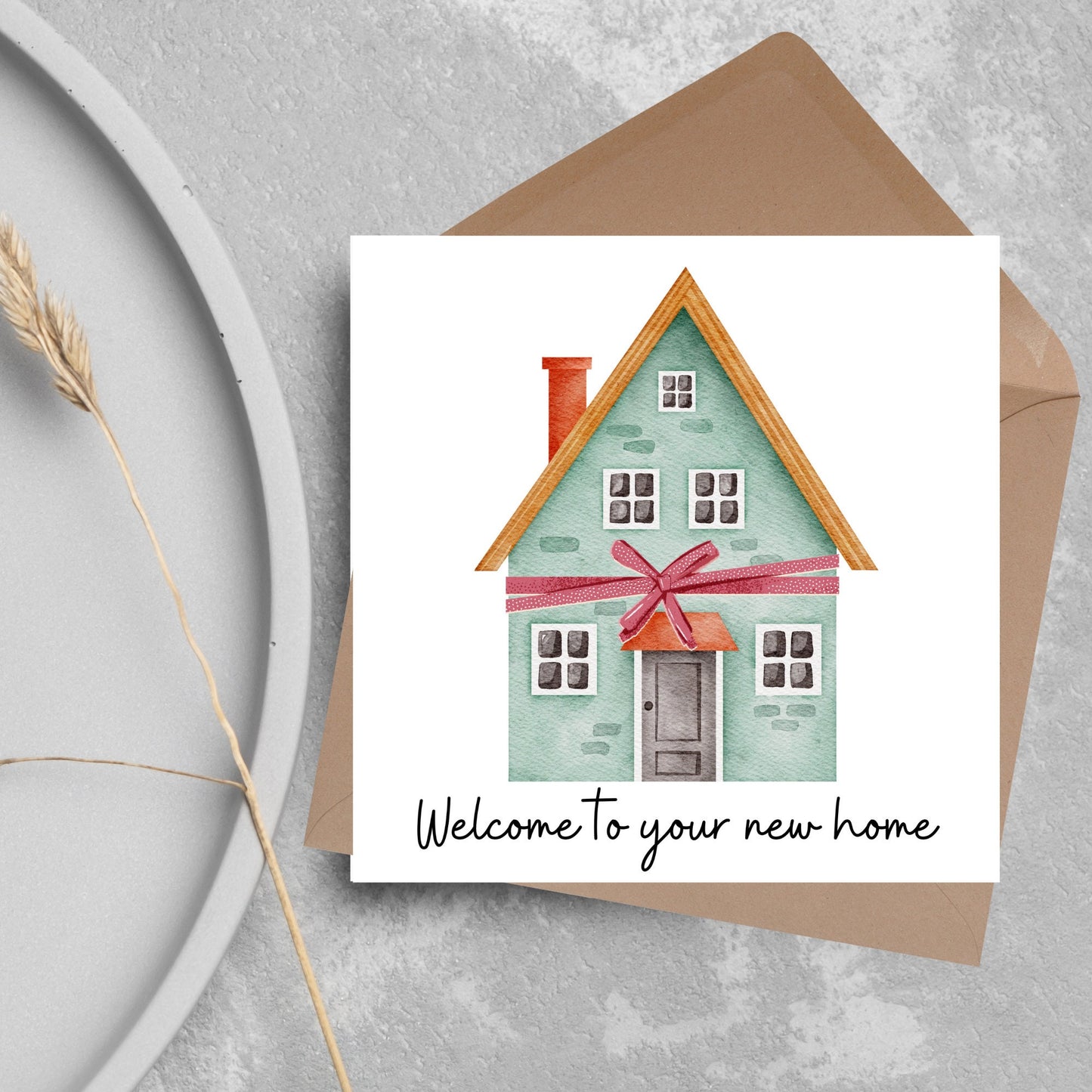 Square card with white background and a watercolour style illlustration of a green three storey house with a red bow wrapped around it. Underneath the house ina script font are the words 'welcome to your new home'