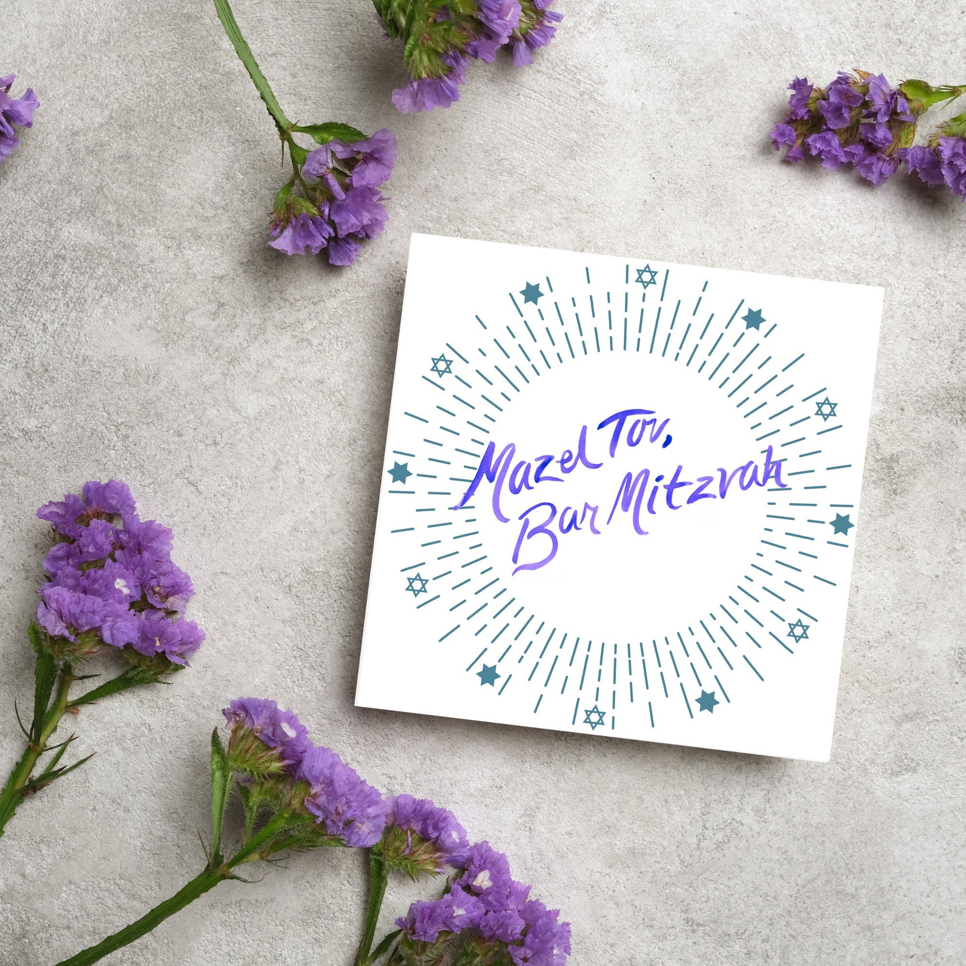 square bar mitzvah card with a white background and the text 'mazel tav, bar mitzvah' in the centre in a blue handwritten script style font. Surrounding the text is a circle made of concentric blue lines and 12 stars of david