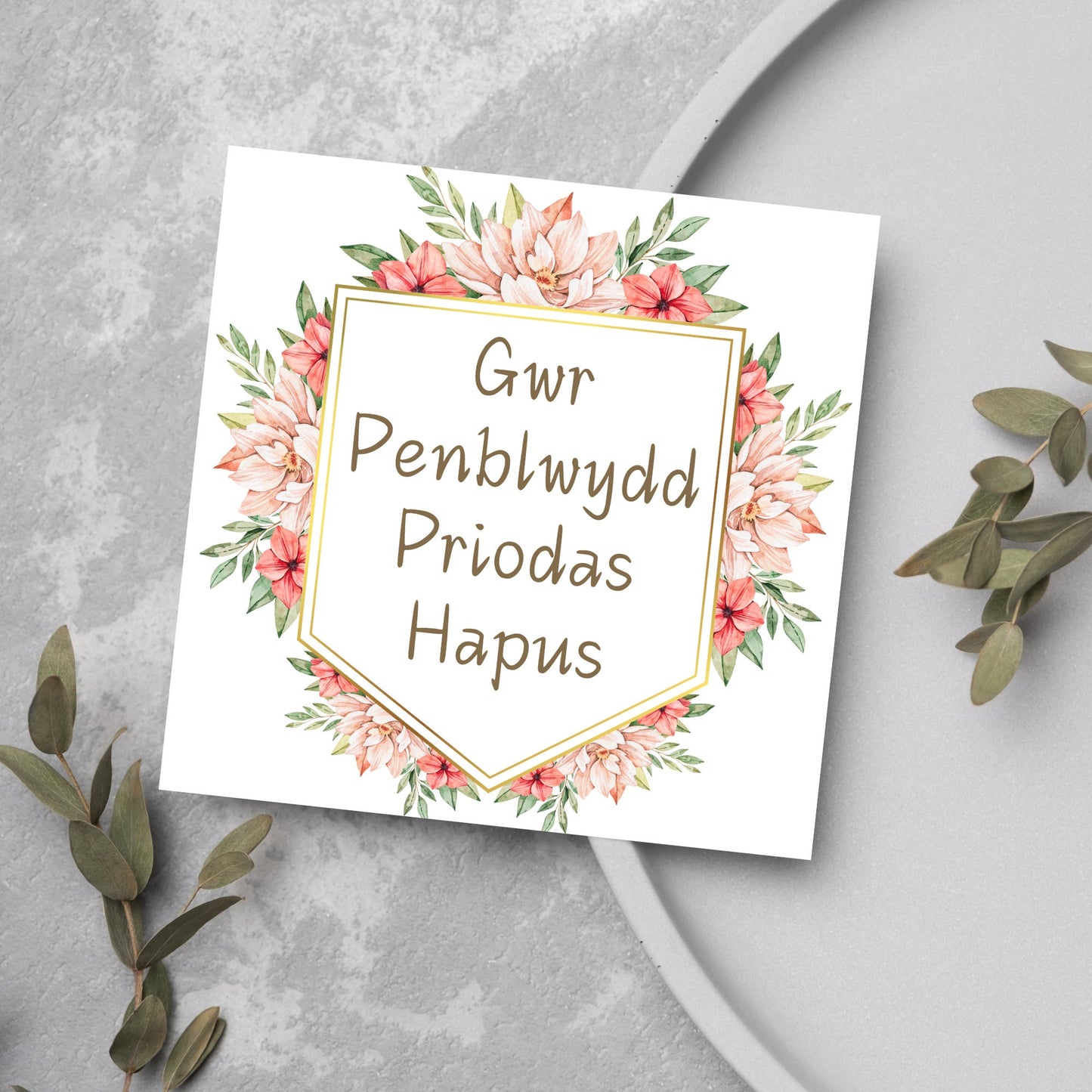 Image of a square wedding anniversary card with 'gwr penblwydd priodas hapus' in a subtle handwritten style font, which translates to 'happy wedding anniversary' in welsh. the text is against a white banner surrounded by pink flowers
