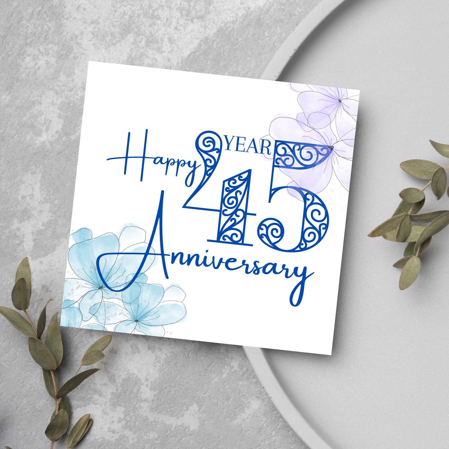 Square Card with white background, there are blue faded watercolour flowers on each corner and dark blue text reads 'Happy 45 year anniversary' the words are in a script font and the number is an ornate filigree style