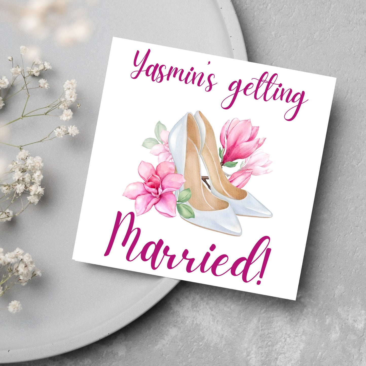 Square card with a watercolour image of white wedding shoes surrounded by pink flowers with pink text that reads Yasmin's getting married in calligraphy style font