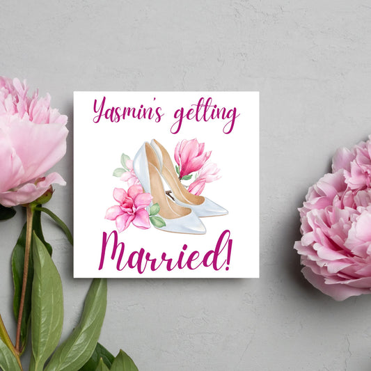 Square card with a watercolour image of white wedding shoes surrounded by pink flowers with pink text that reads Yasmin's getting married in calligraphy style font