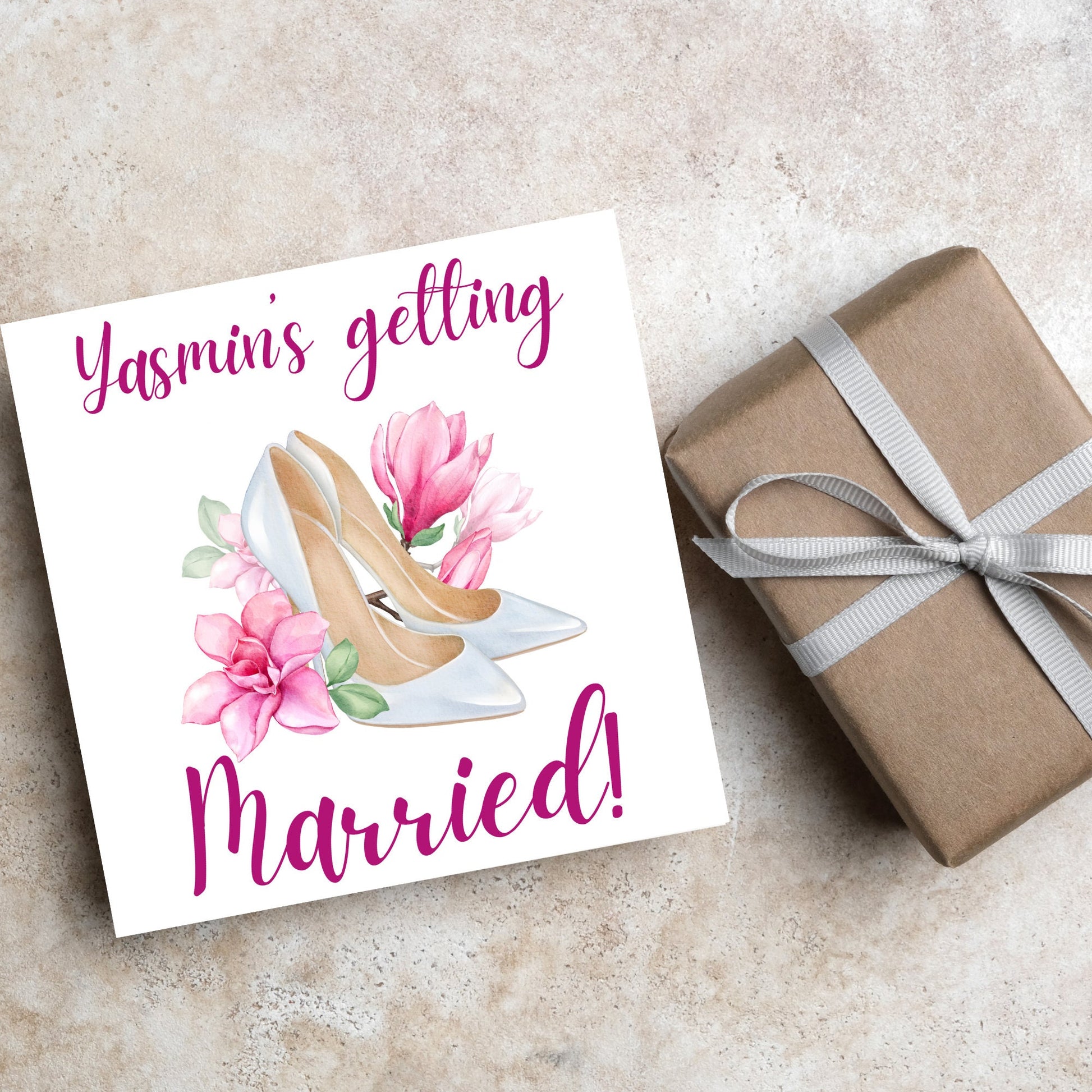 Square card with a watercolour image of white wedding shoes surrounded by pink flowers with pink text that reads Yasmin's getting married in calligraphy style font