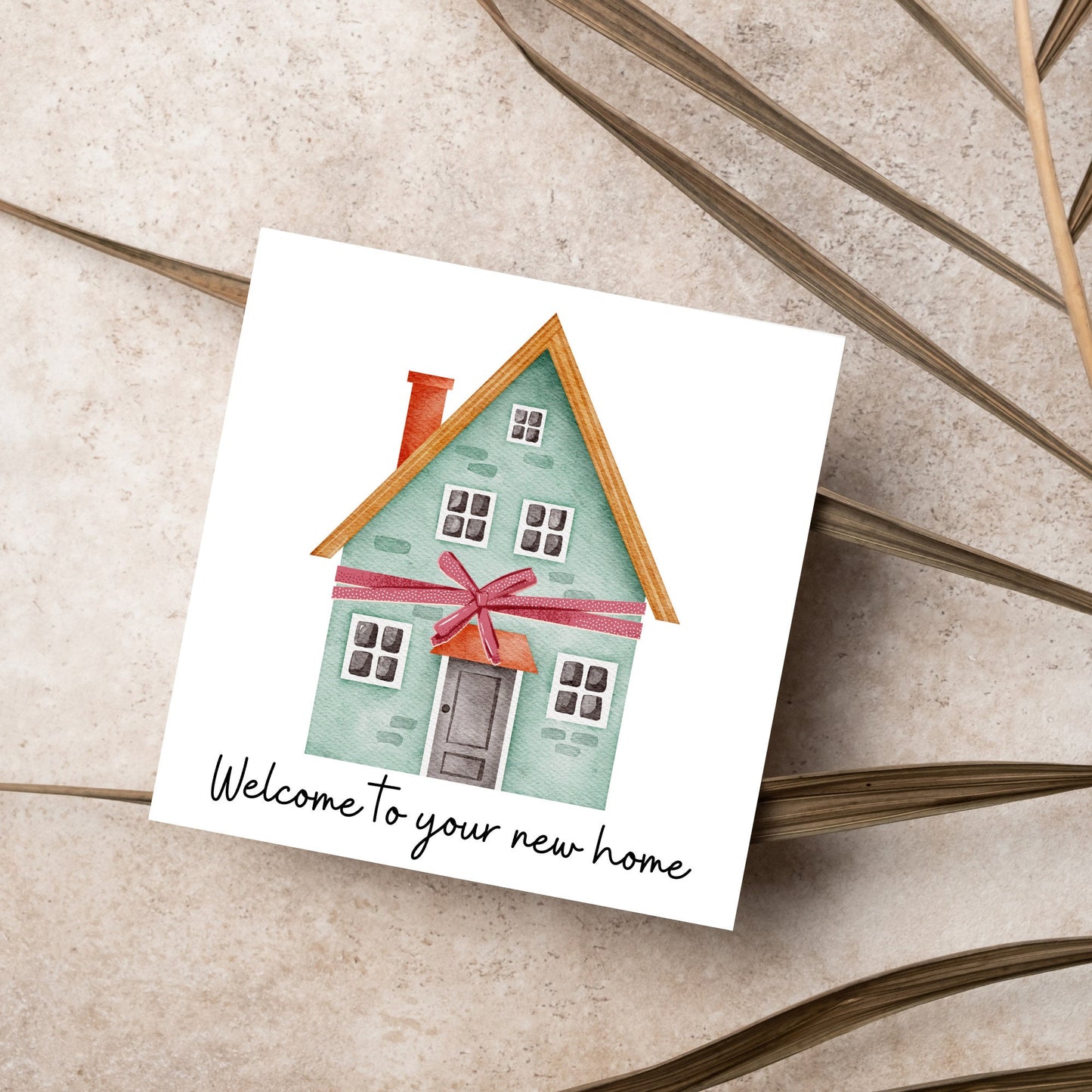 Square card with white background and a watercolour style illlustration of a green three storey house with a red bow wrapped around it. Underneath the house ina script font are the words 'welcome to your new home'