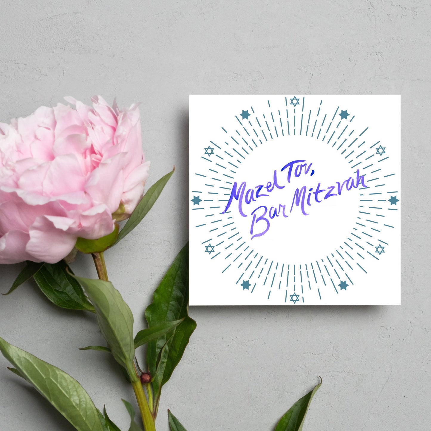 square bar mitzvah card with a white background and the text 'mazel tav, bar mitzvah' in the centre in a blue handwritten script style font. Surrounding the text is a circle made of concentric blue lines and 12 stars of david