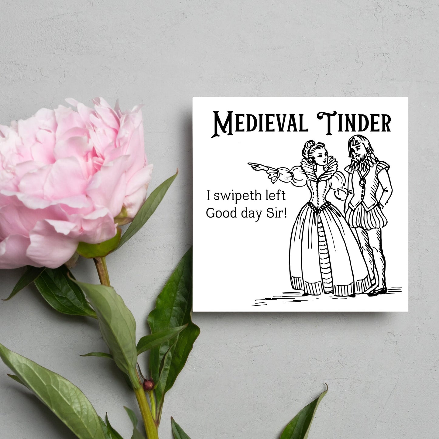 image of a square greetings card with a black and white hand drawn vintage style illustration of medieval man and woman, the woman pointing left and the text - medieval tinder. I swipeth left. Good day Sir! - in a vintage blackletter font