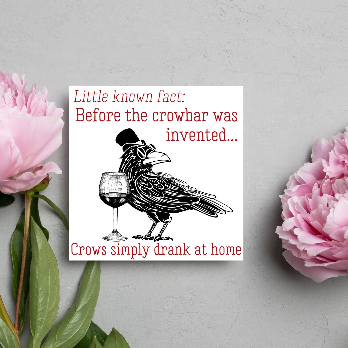 image of a square greetings card with a black and white drawing of a crow wearing a top hat and spectacles, standing next to a half empty glass of wine and the text - little known fact: before the crowbar was invented...crows simply drank at home