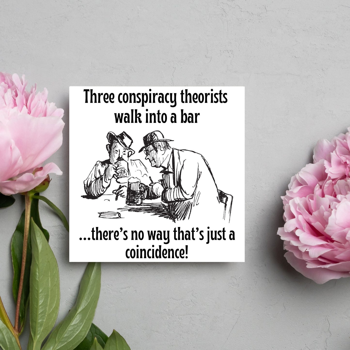 Image of a square greetings card with a hand drawn black and white line cartoon sketch of two old men at a bar drinking beer with the text- 3 conspiracy theorists walk into a bar....there's no way that's just a coincidence!