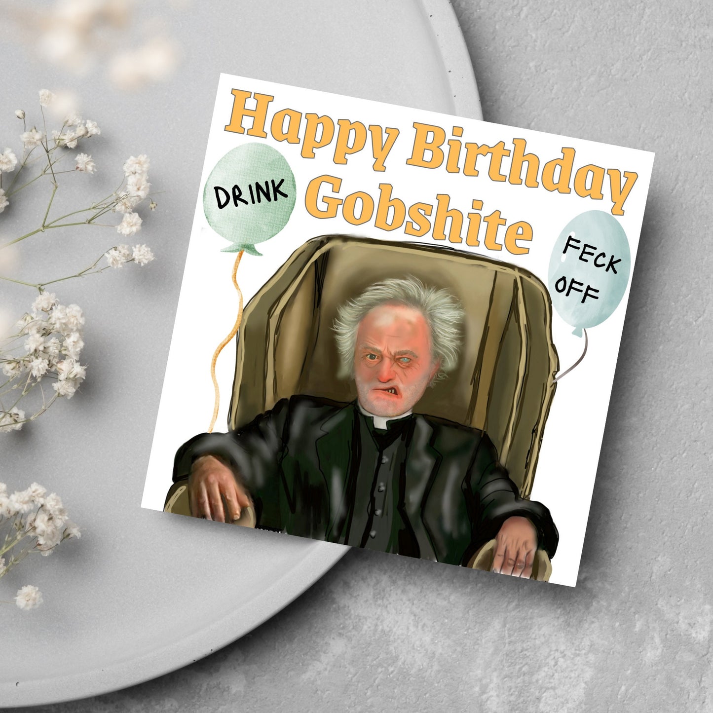 square birthday card with a hand drawn image of father jack from the tv show father ted. he is sitting in his chair looking mean with the text happy birthday gobshite above him. 2 balloons are next to him with feck off and drink on them