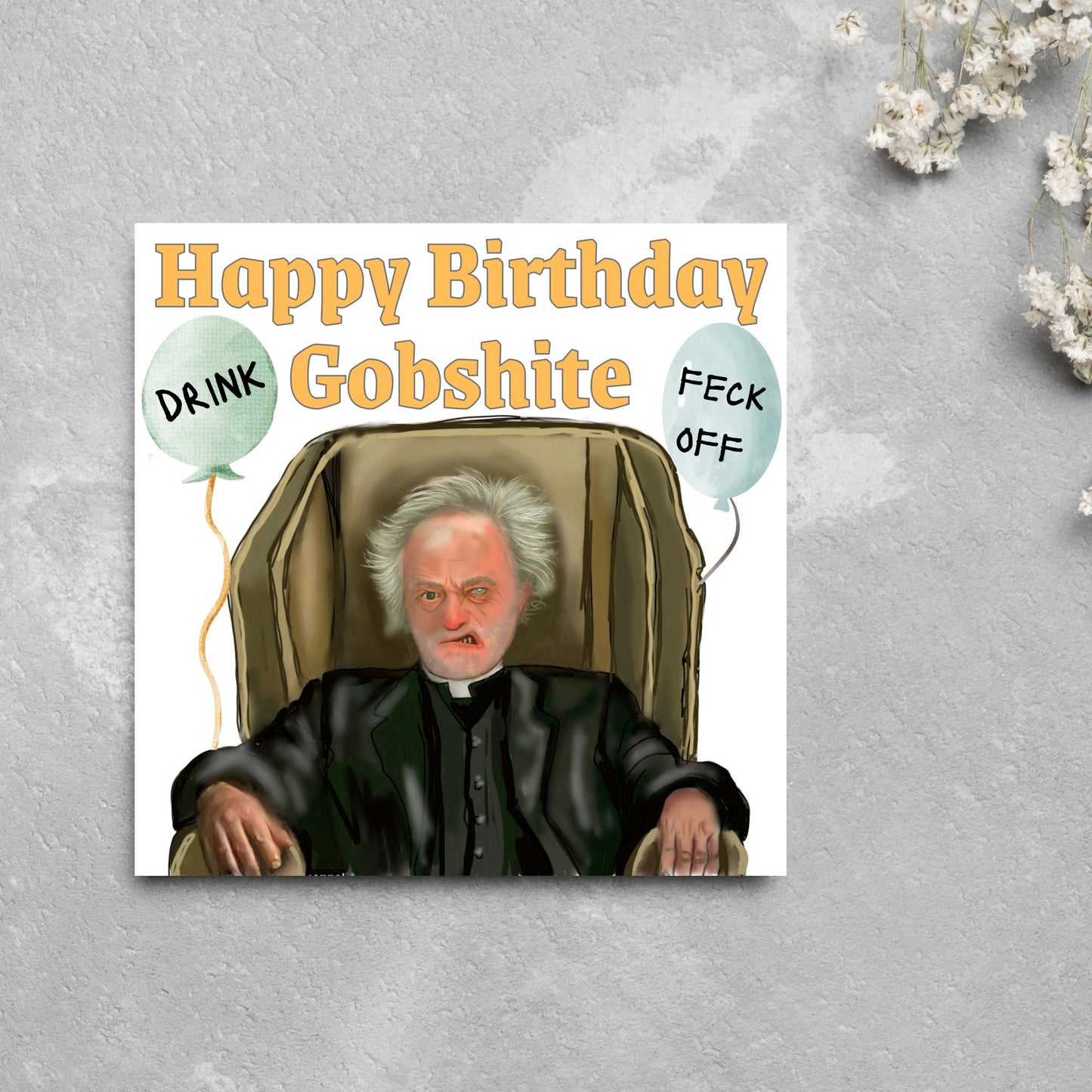 square birthday card with a hand drawn image of father jack from the tv show father ted. he is sitting in his chair looking mean with the text happy birthday gobshite above him. 2 balloons are next to him with feck off and drink on them
