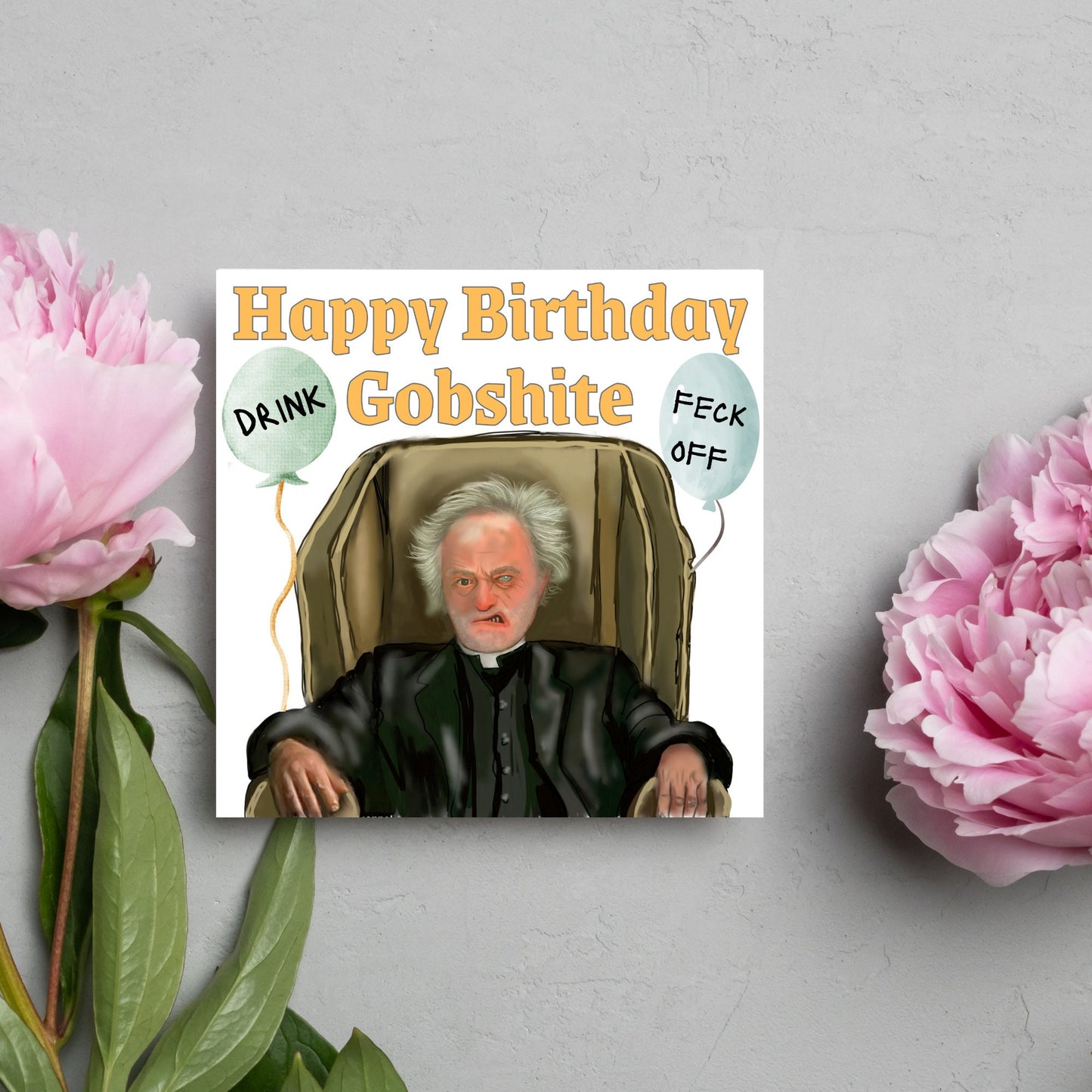 square birthday card with a hand drawn image of father jack from the tv show father ted. he is sitting in his chair looking mean with the text happy birthday gobshite above him. 2 balloons are next to him with feck off and drink on them