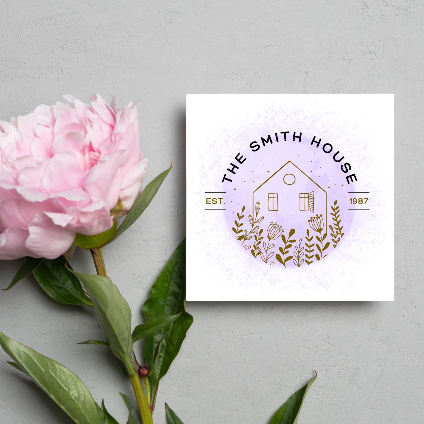 square card with a purple watercolour circle with a line drawing of a house and foliage over it. Arched text reads the smith house on top with est 1987 running through the centre