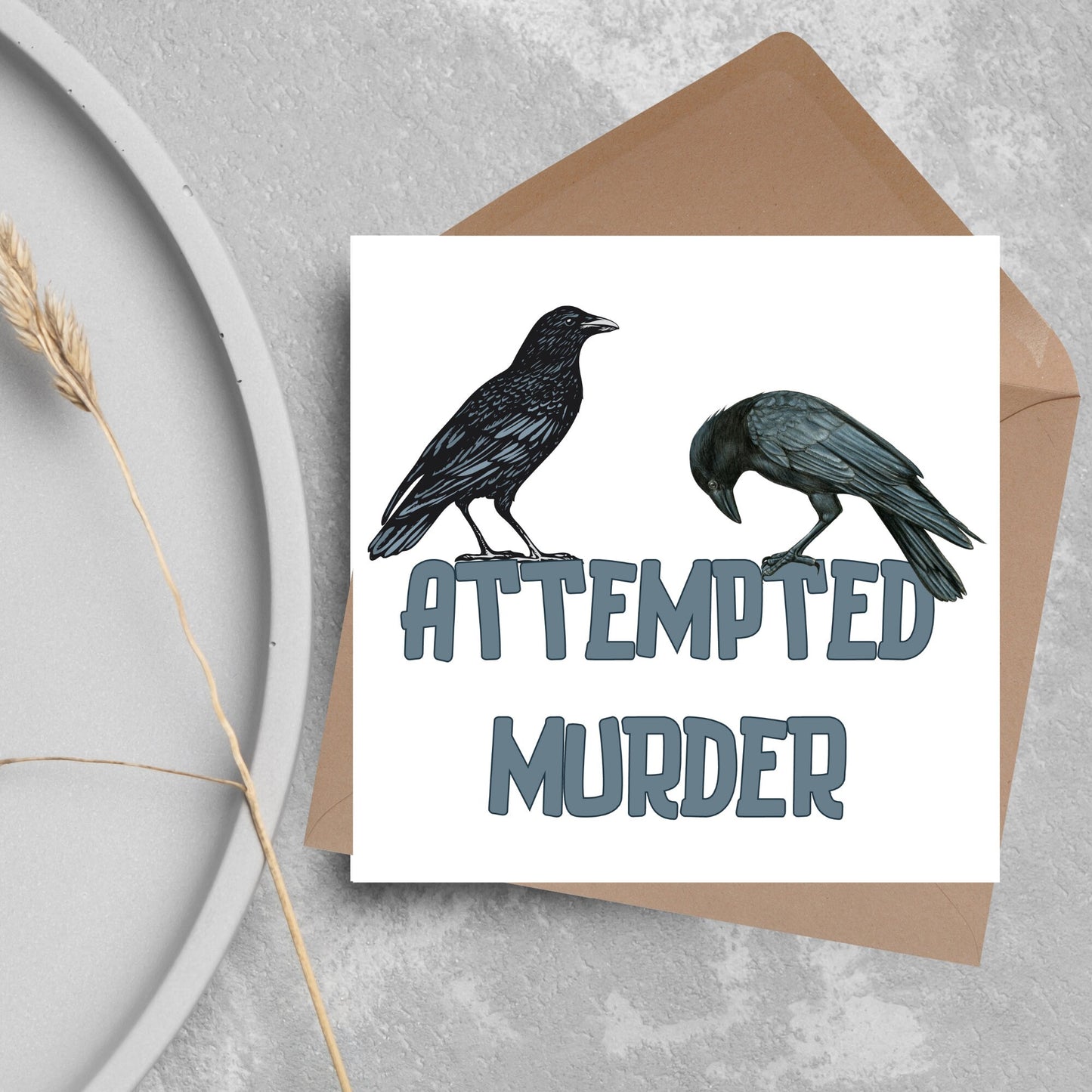 square card with the words attempted murder and 2 crows sitting on top of the text (a murder is the collective name 3 or more crows)