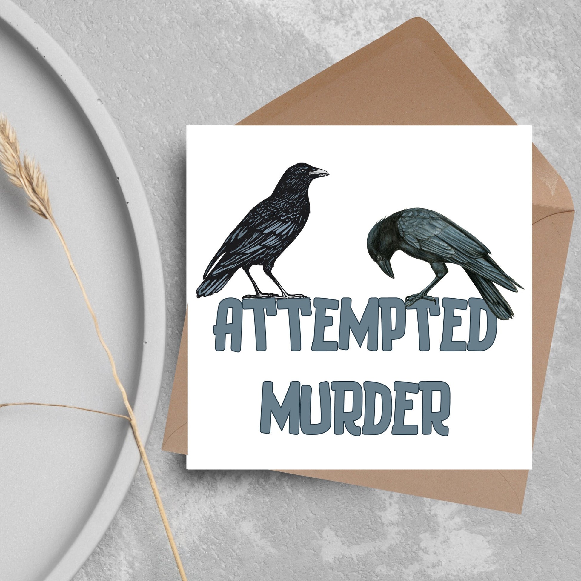 square card with the words attempted murder and 2 crows sitting on top of the text (a murder is the collective name 3 or more crows)