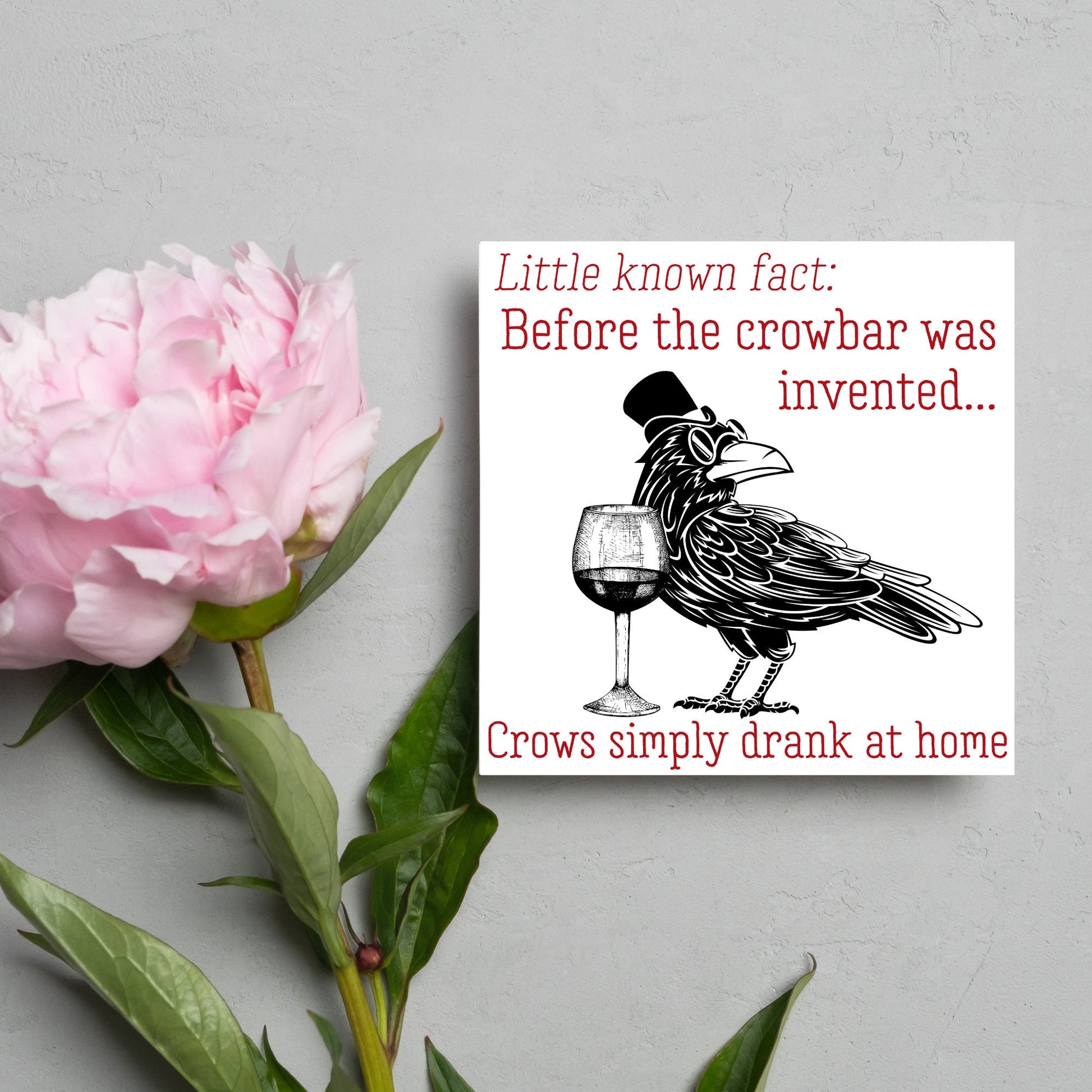 image of a square greetings card with a black and white drawing of a crow wearing a top hat and spectacles, standing next to a half empty glass of wine and the text - little known fact: before the crowbar was invented...crows simply drank at home
