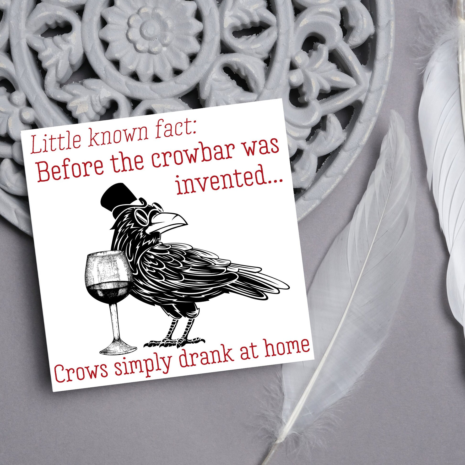 image of a square greetings card with a black and white drawing of a crow wearing a top hat and spectacles, standing next to a half empty glass of wine and the text - little known fact: before the crowbar was invented...crows simply drank at home