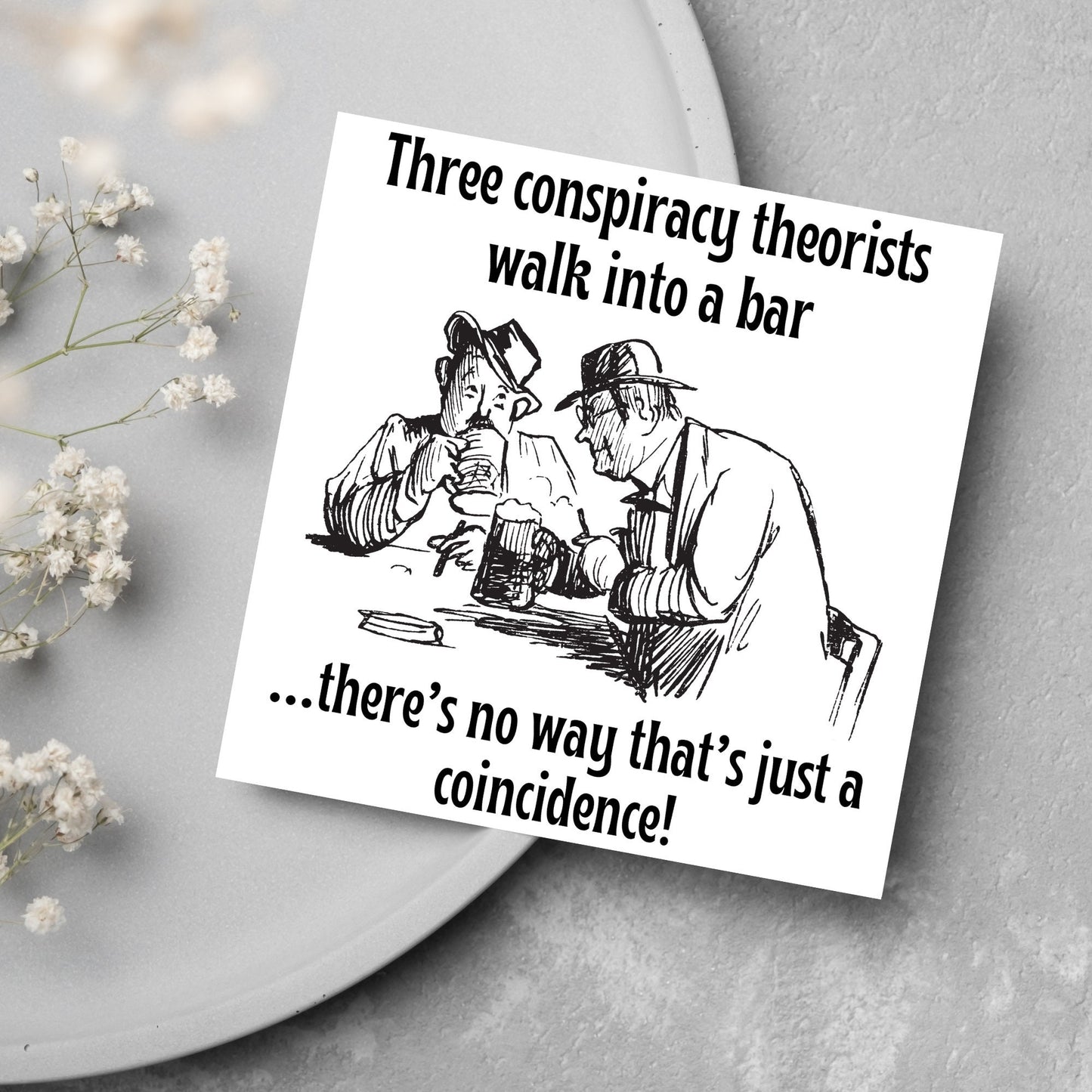 Image of a square greetings card with a hand drawn black and white line cartoon sketch of two old men at a bar drinking beer with the text- 3 conspiracy theorists walk into a bar....there's no way that's just a coincidence!