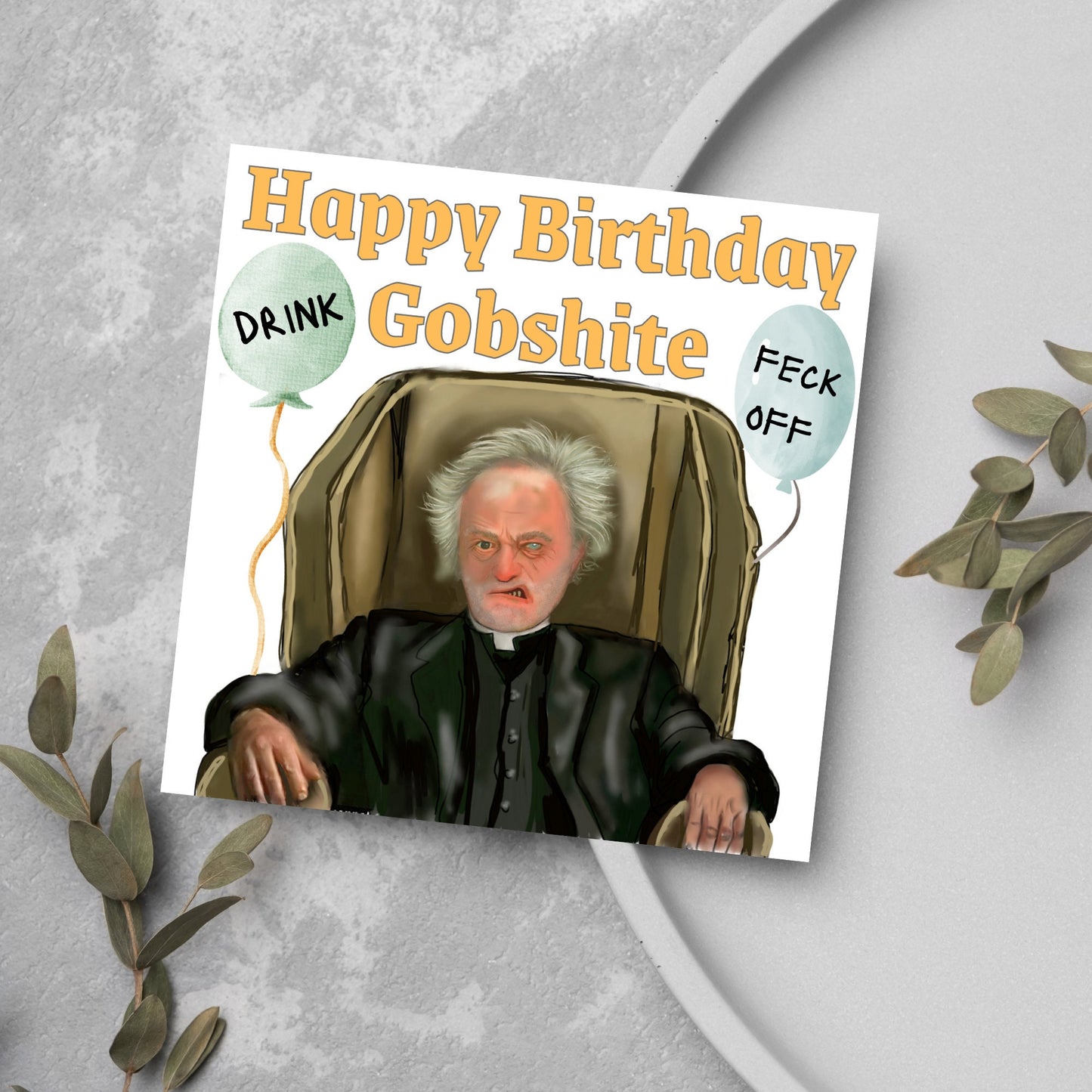 square birthday card with a hand drawn image of father jack from the tv show father ted. he is sitting in his chair looking mean with the text happy birthday gobshite above him. 2 balloons are next to him with feck off and drink on them