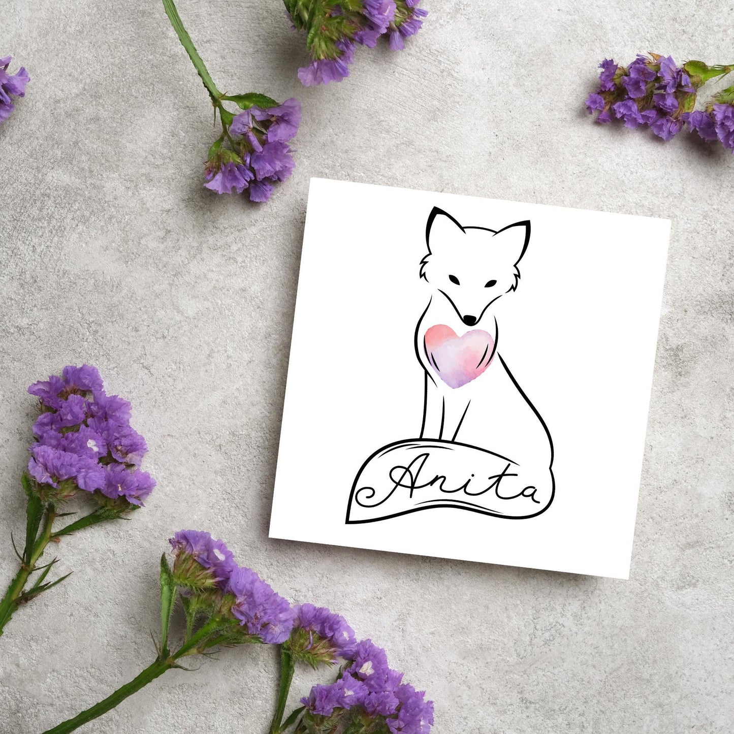 Square card with simple black line drawing of a fox sitting with its tail wrapped around its feet. It has a pink watercolour heart on its chest and personalised with a name on the tail in a calligraphy font